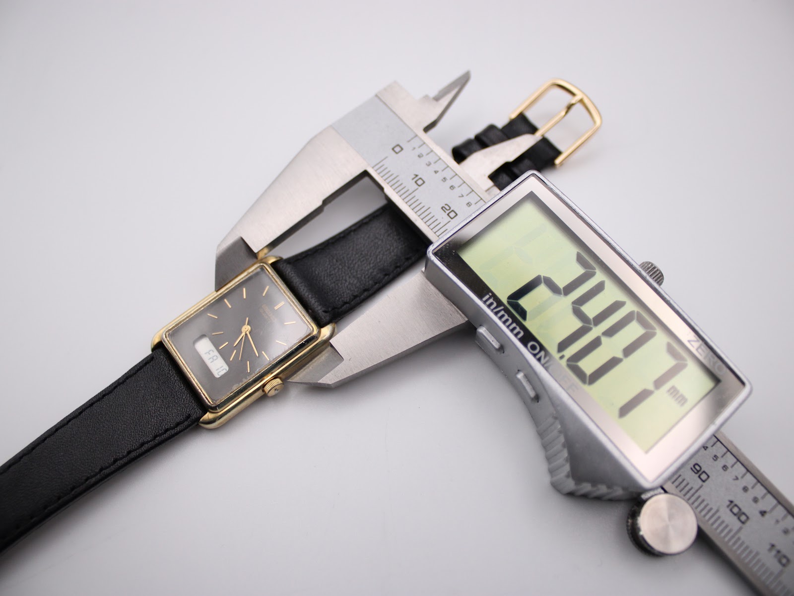 A digital caliper measuring the case width of the Seiko watch, with the display showing "24.77mm".