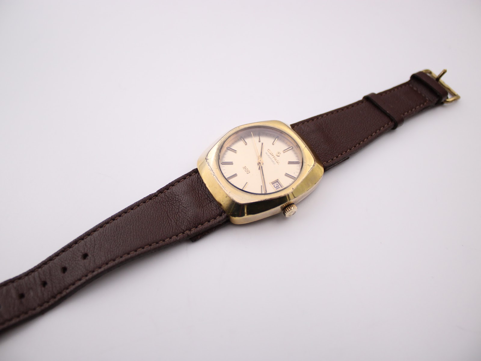 Overhead view of the Certina 288 watch laid flat, showing the full brown leather strap and gold-tone buckle.