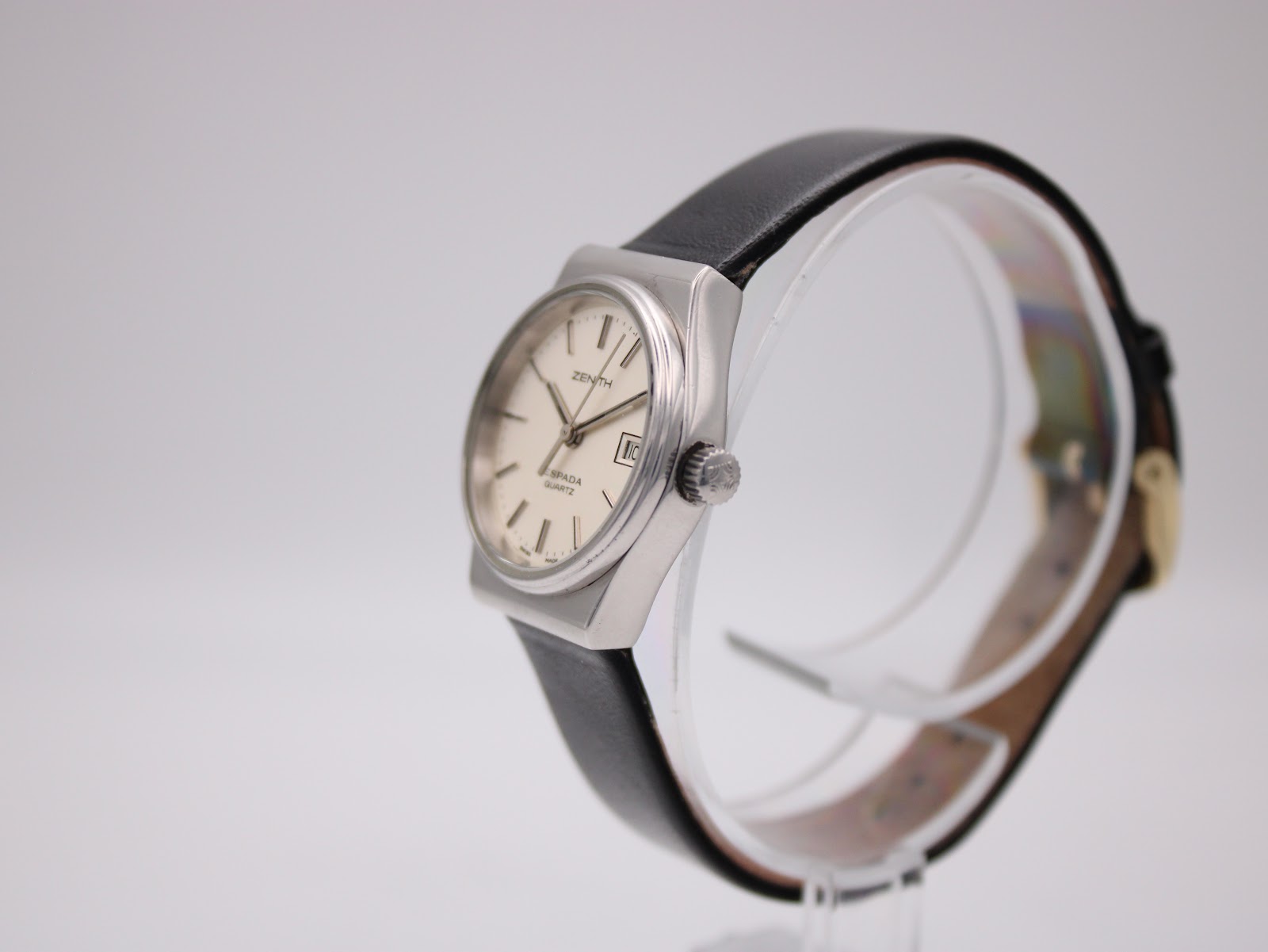 Angled side view of the Zenith Espada watch, showing the crown and case profile on a clear watch stand.