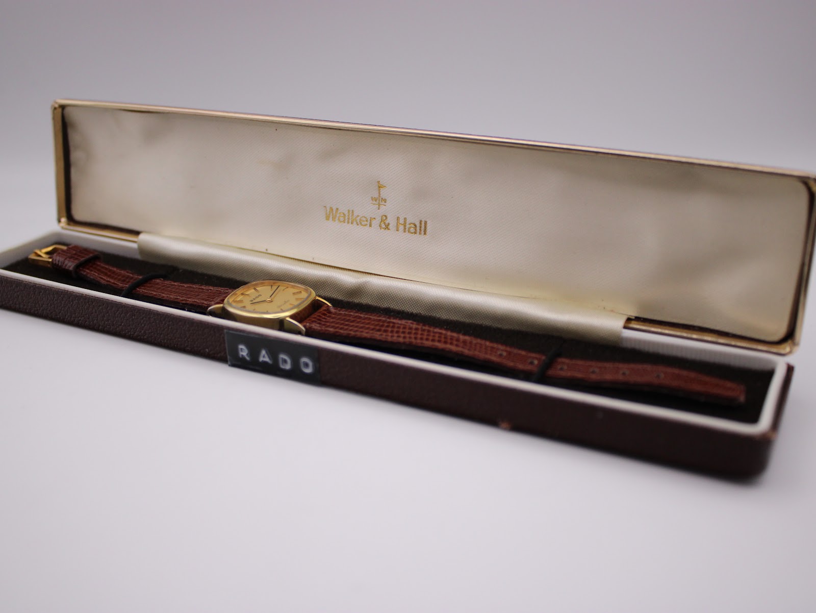 Rado Silhouette watch in a generic brown presentation box with 'Walker & Hall' logo.