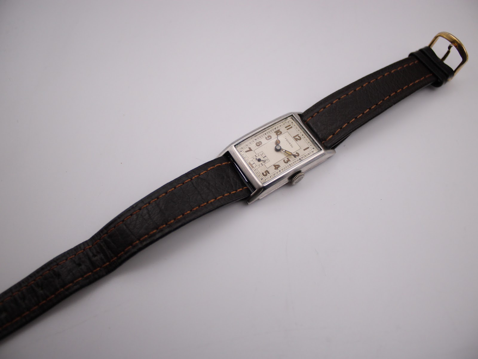 Top-down view of the PRONTO watch laid flat, displaying the brown leather strap and overall length.