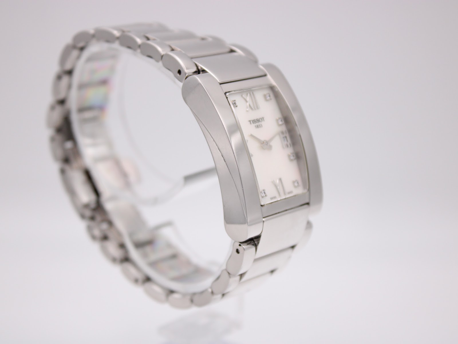 Angled side view of the Tissot t007309 a watch on a stand, showing the left side of the rectangular case and bracelet links.