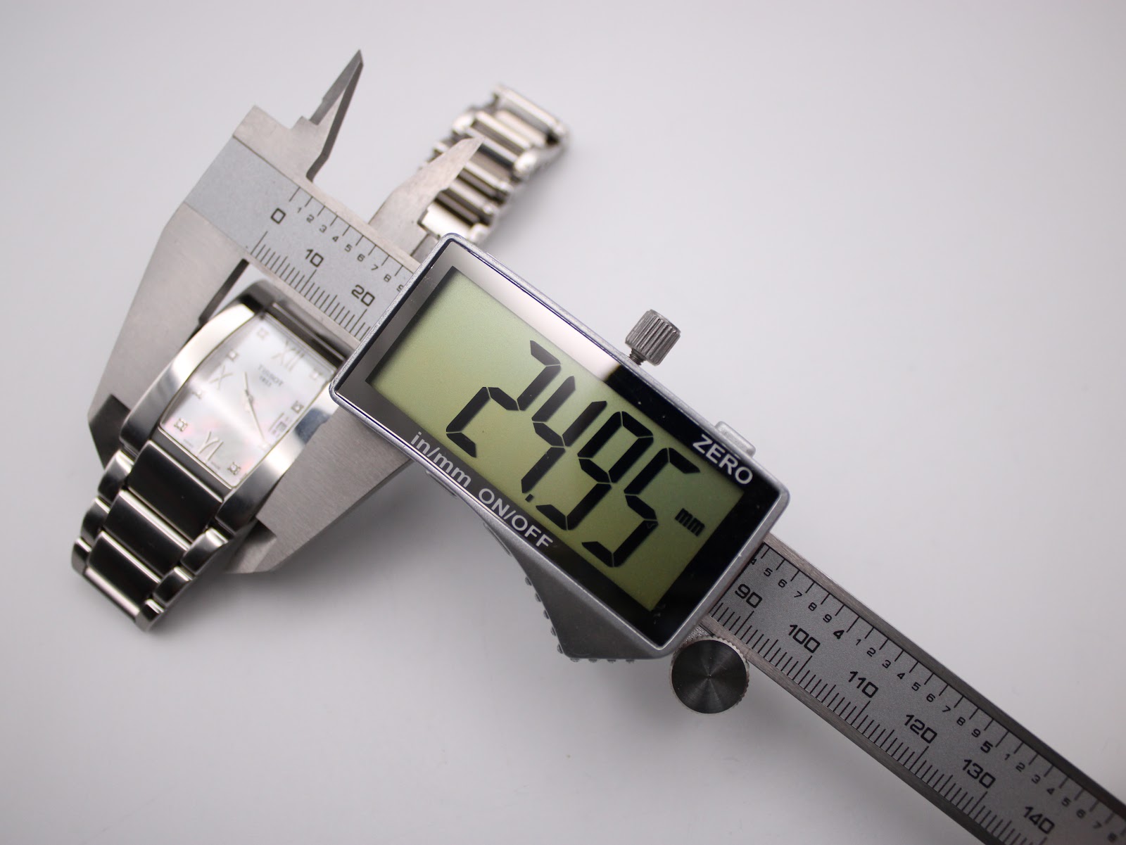 Digital caliper measuring the Tissot watch case width at 24.95 mm, showing the precise measurement.