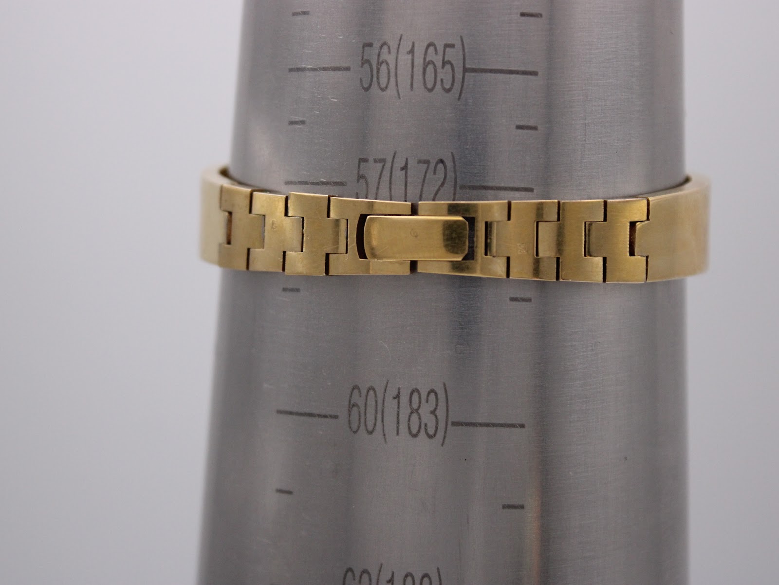 The gold-tone integrated bracelet of the watch shown on a metal wrist sizing gauge, indicating a circumference of approximately 168.5mm.