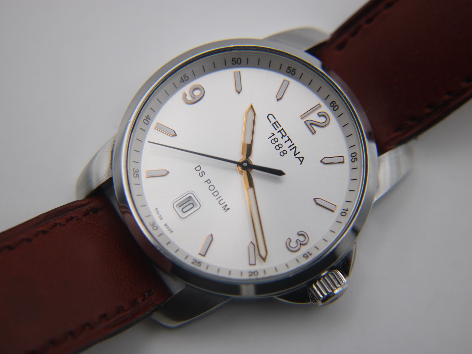 Angled close-up of the Certina DS Podium dial, highlighting the white face, Arabic numerals, and dauphine hands.