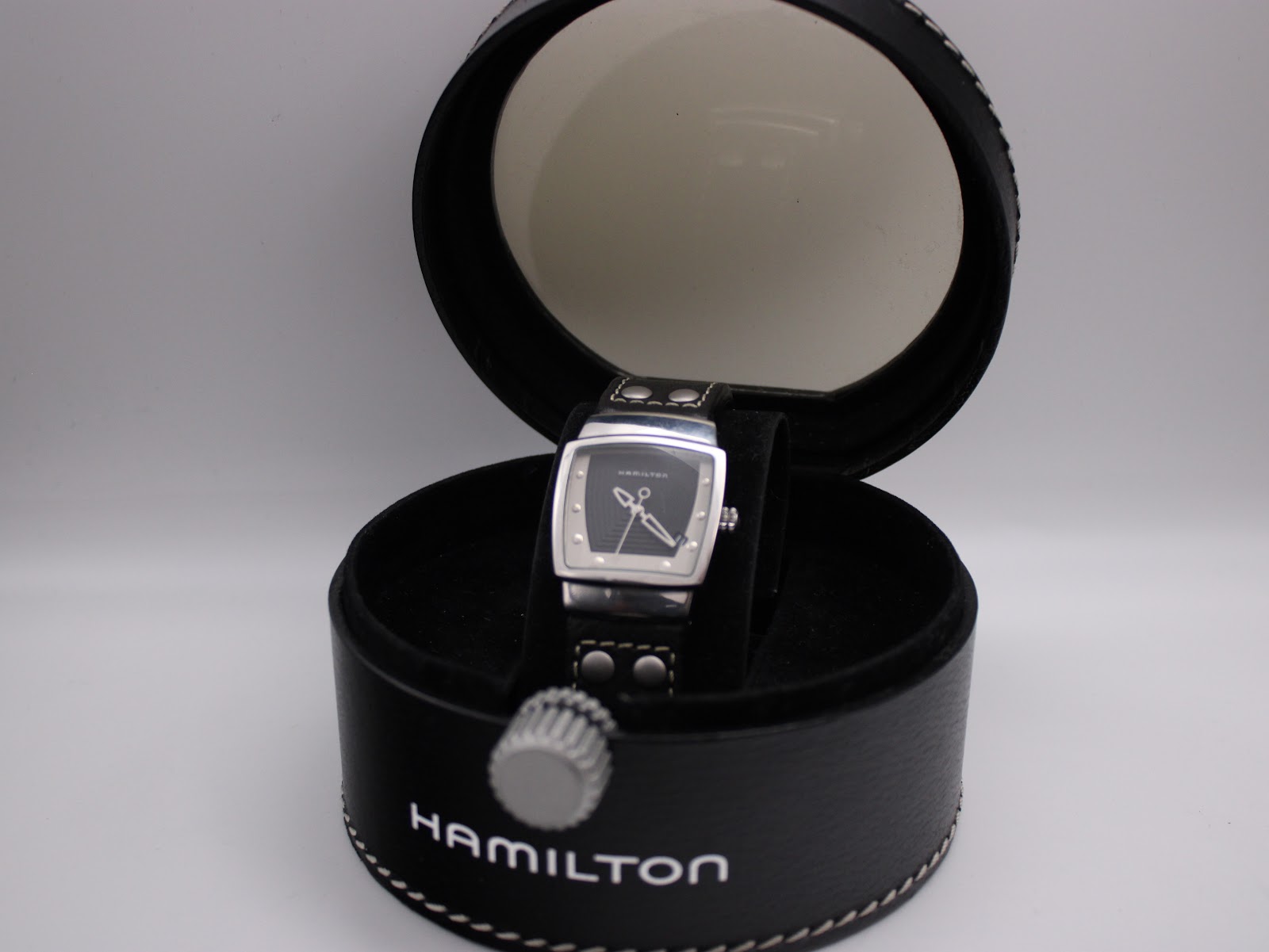 Hamilton H163110 quartz watch in original black leatherette box with white stitching and transparent lid.
