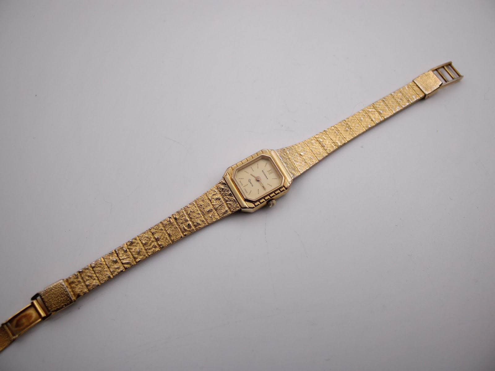 Full view of the Bucherer watch laid out, showcasing the entire integrated gold-tone mesh bracelet.