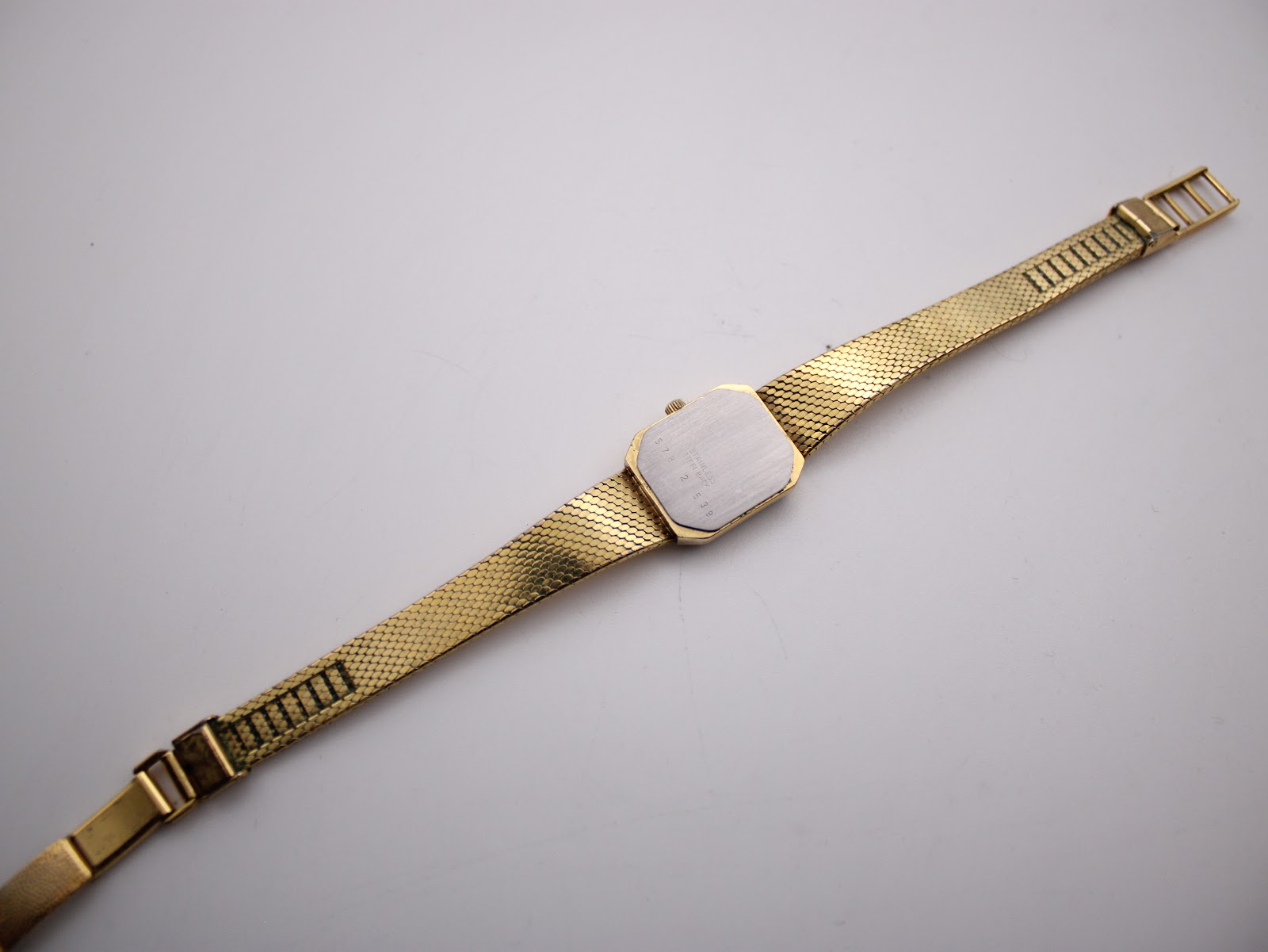 Full back view of the Bucherer watch laid out, showing the stainless steel case back and the full length of the bracelet.