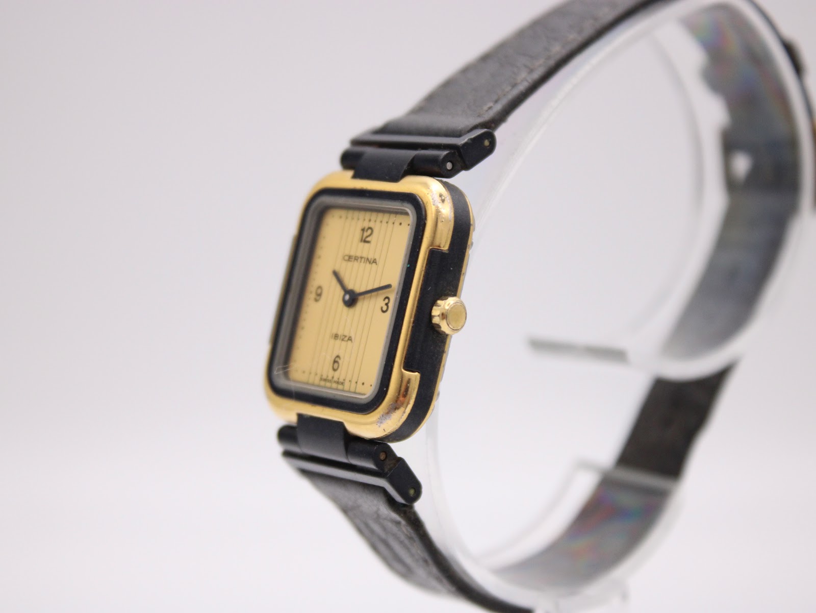 Angled side view of the Certina Ibiza watch on a stand, highlighting the gold case profile and crown
