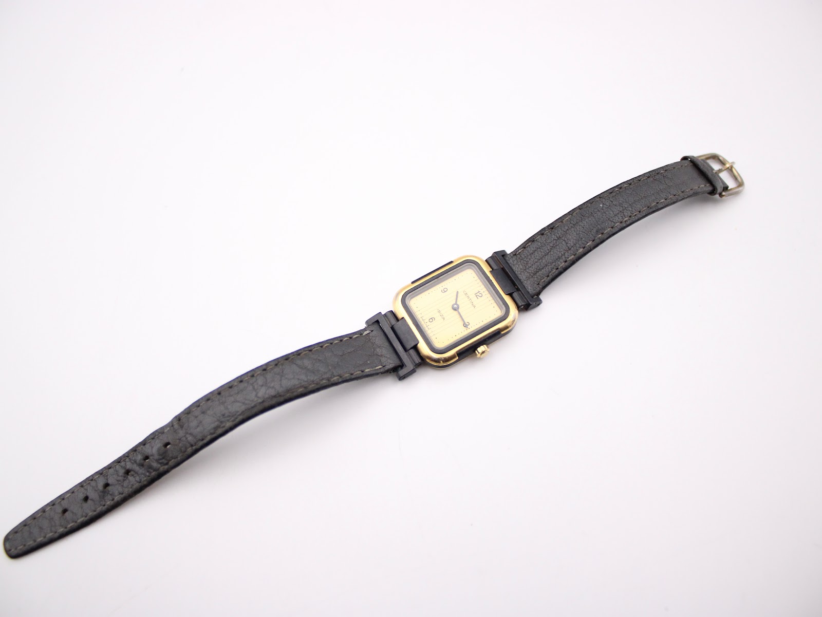 Full overhead view of the Certina Ibiza watch and black leather strap laid flat against a white background