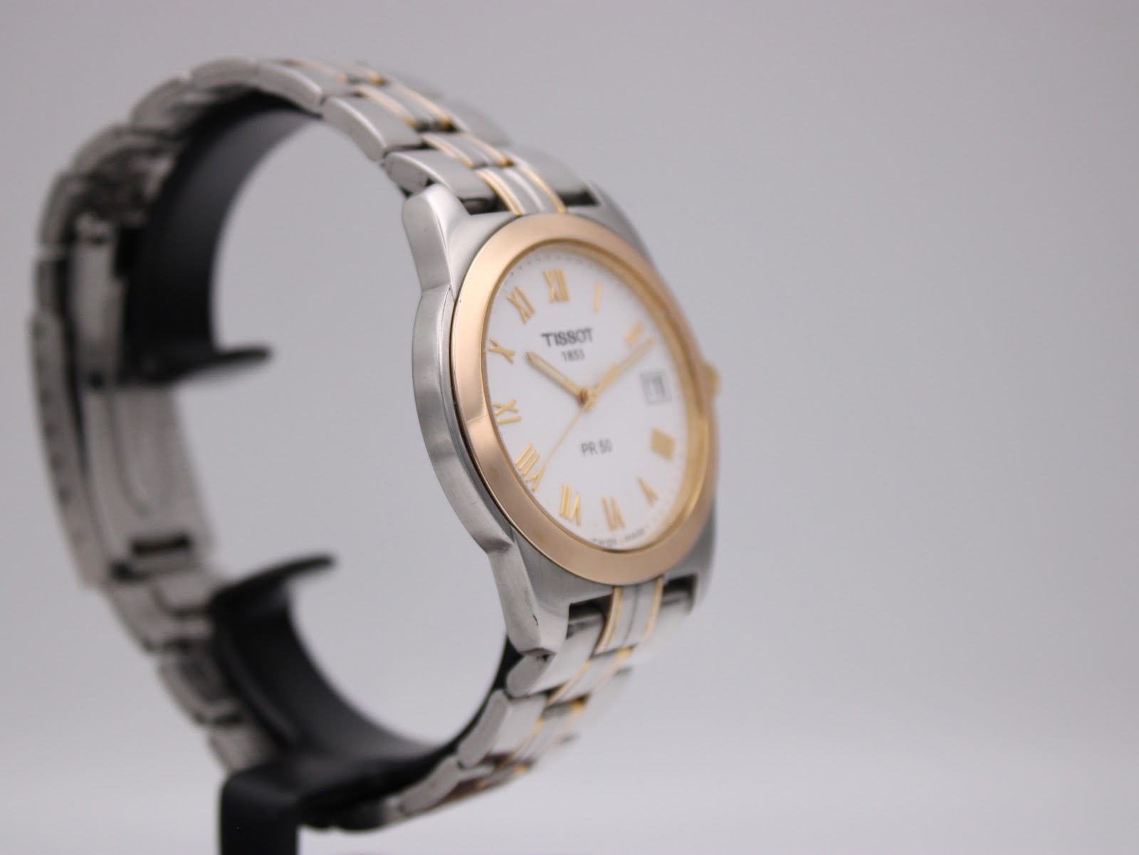 Another angled side view of the Tissot PR 50 watch on a stand, highlighting the case profile.