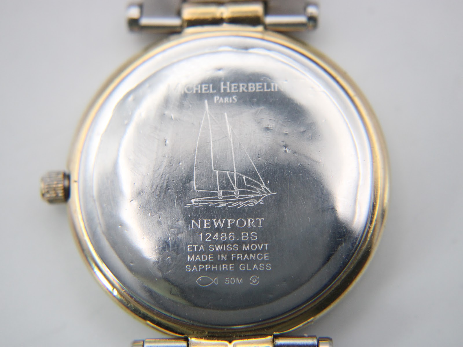 Close-up of the stainless steel case back with "Michel Herbelin Paris", sailboat engraving, model "12486.BS", "ETA Swiss Movt", "Made in France", "Sapphire Glass", and "50M" markings.