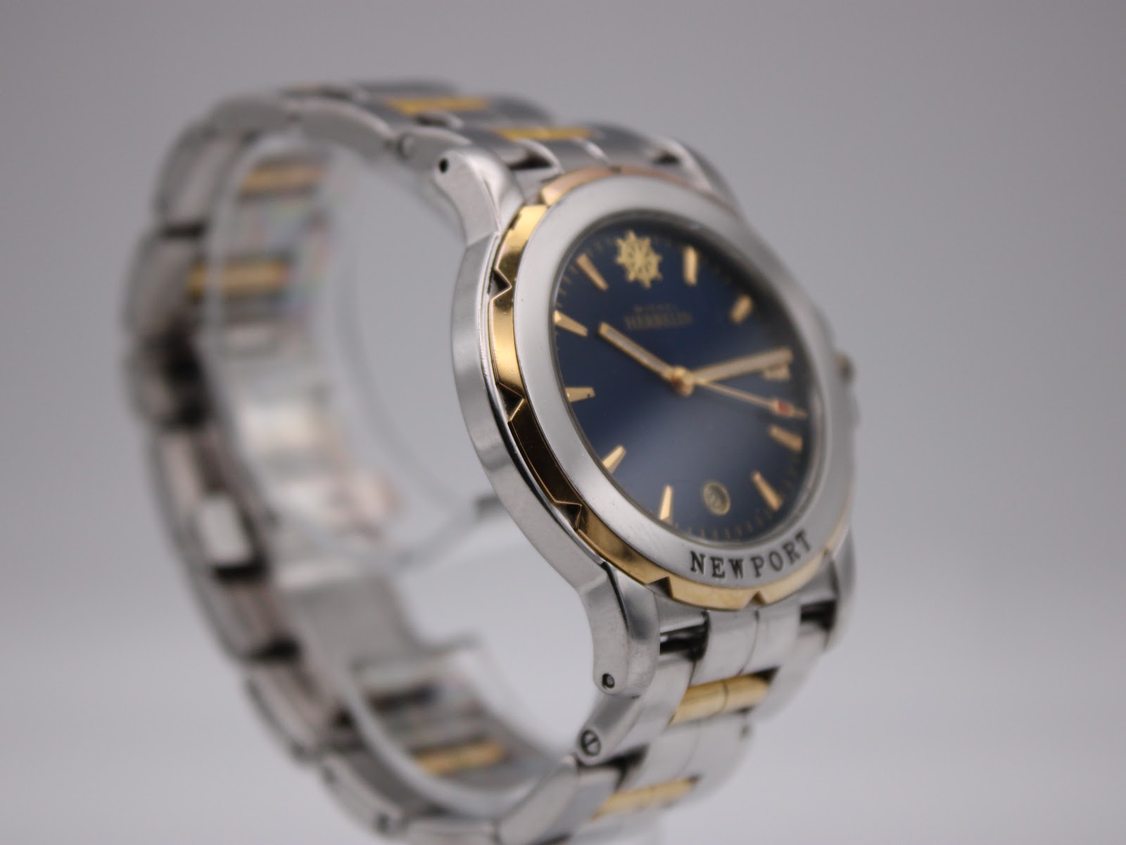 Another angled side view of the watch, emphasising the distinctive gold-tone grooved bezel and the clarity of the blue dial.