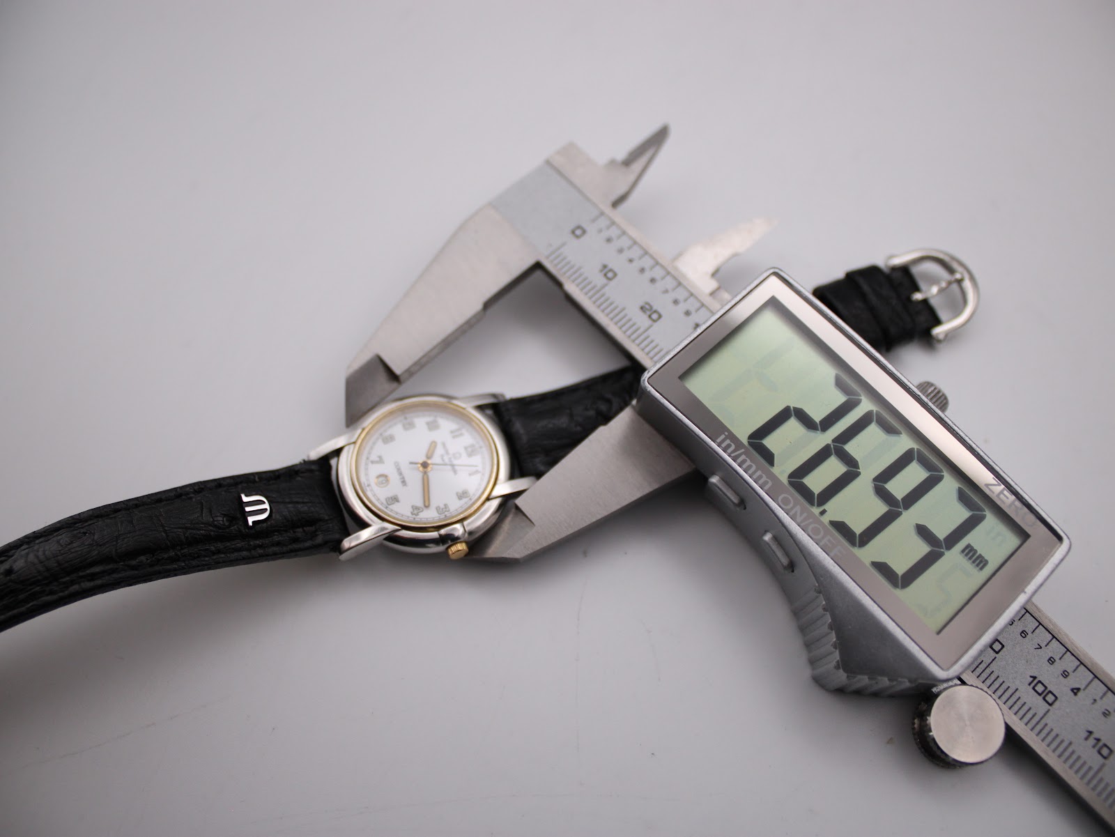 Close-up of a digital caliper measuring the case diameter of the Michel Herbelin watch at 26.93mm.