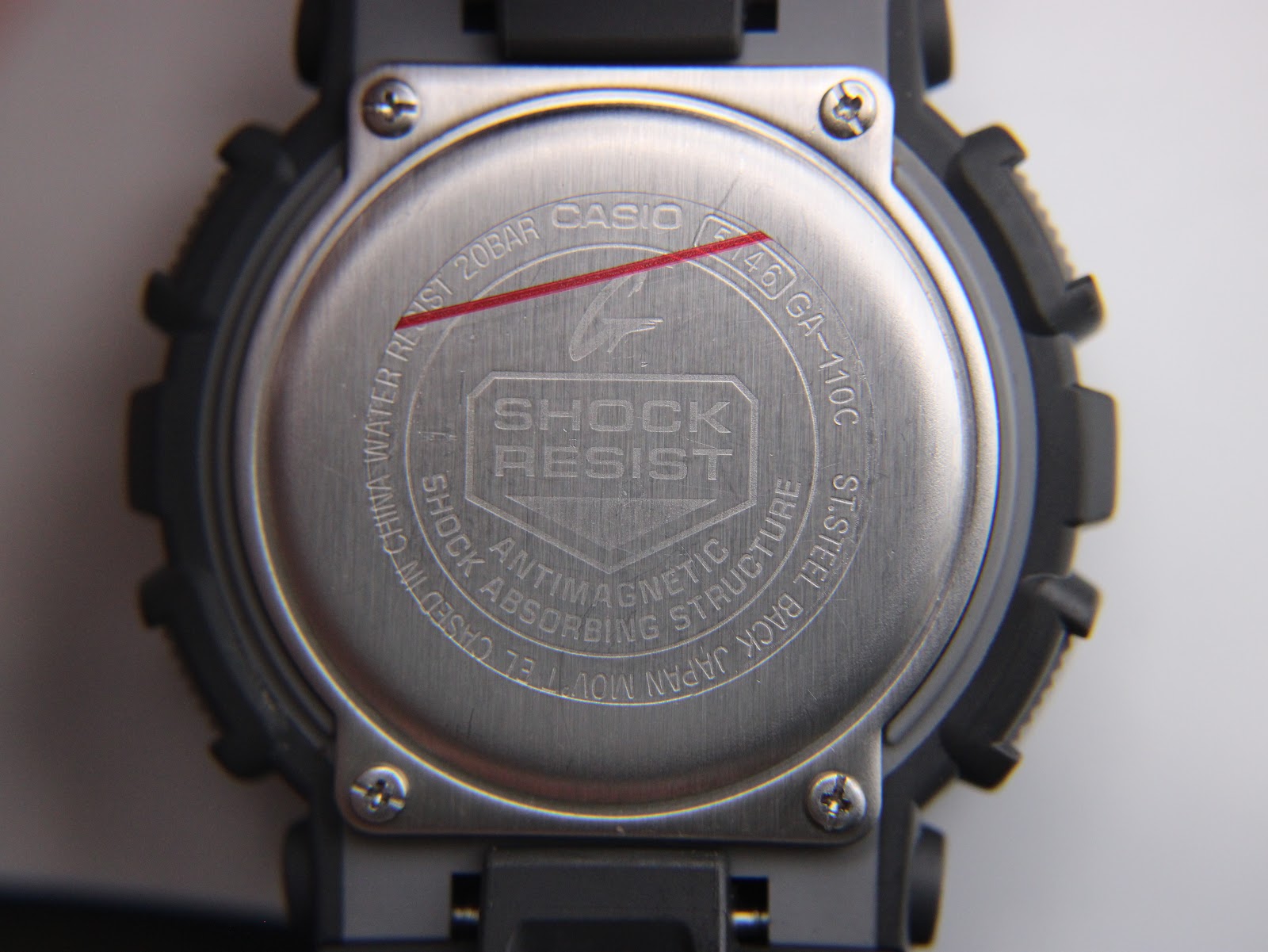 Close-up of the stainless steel case back of the G-Shock GA-110C, showing "SHOCK RESIST", "WATER RESIST 20BAR", and model number.