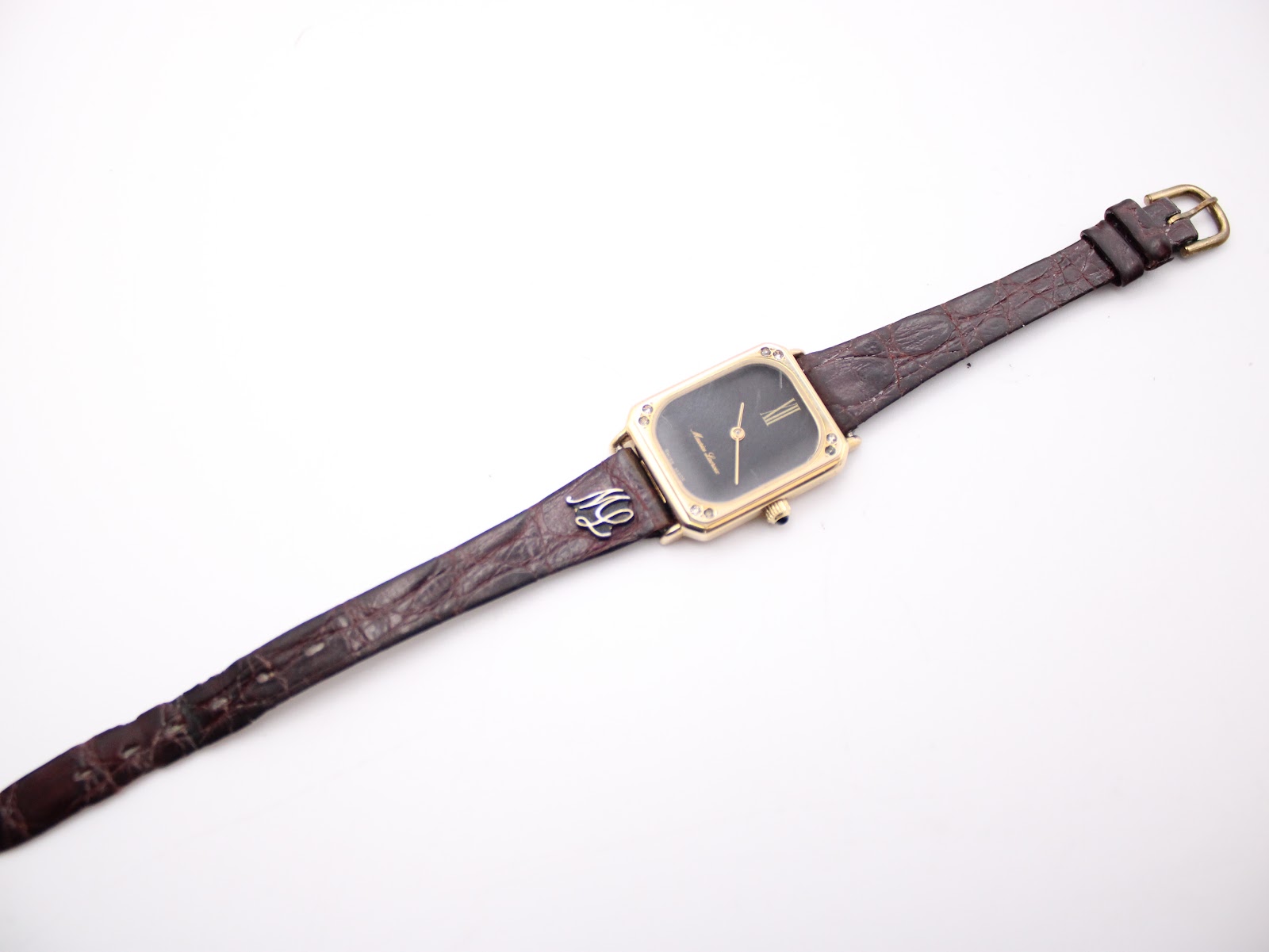 Full length top-down view of the watch and its worn brown leather strap with a gold-tone buckle, against a plain white background.