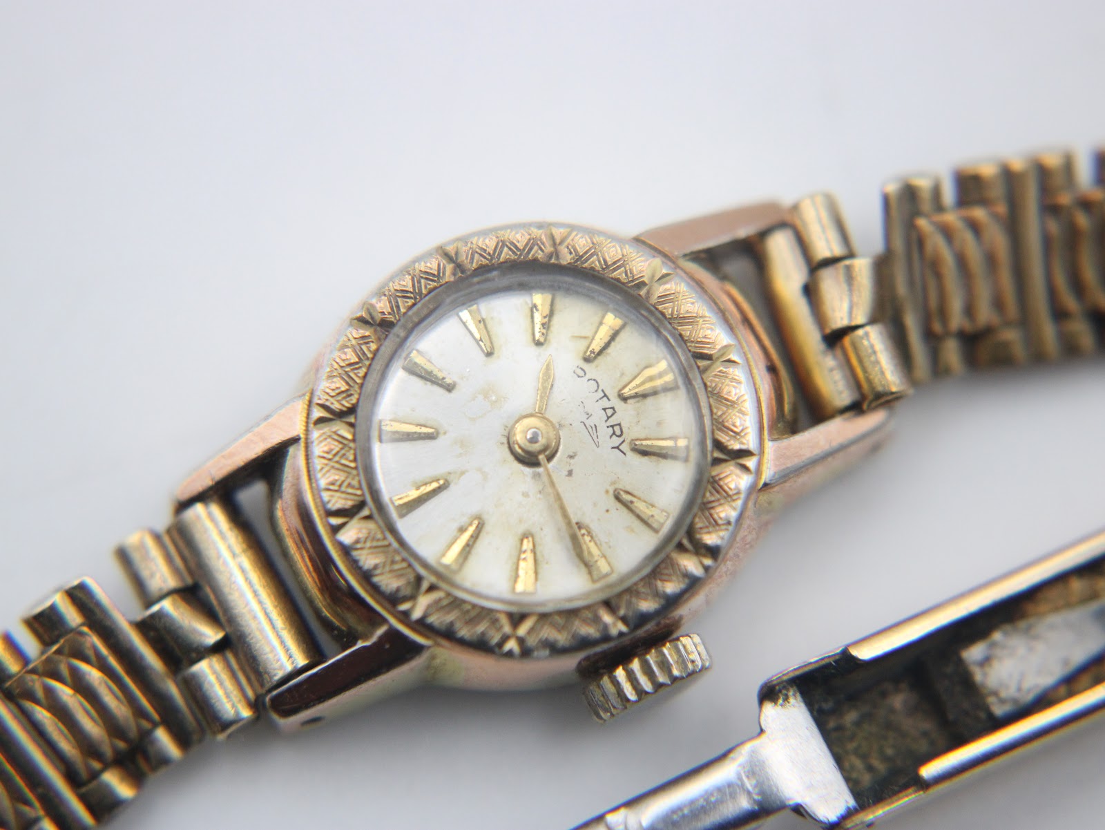 Close-up of the Rotary watch dial, showing the cream face, gold baton indices, and logo.