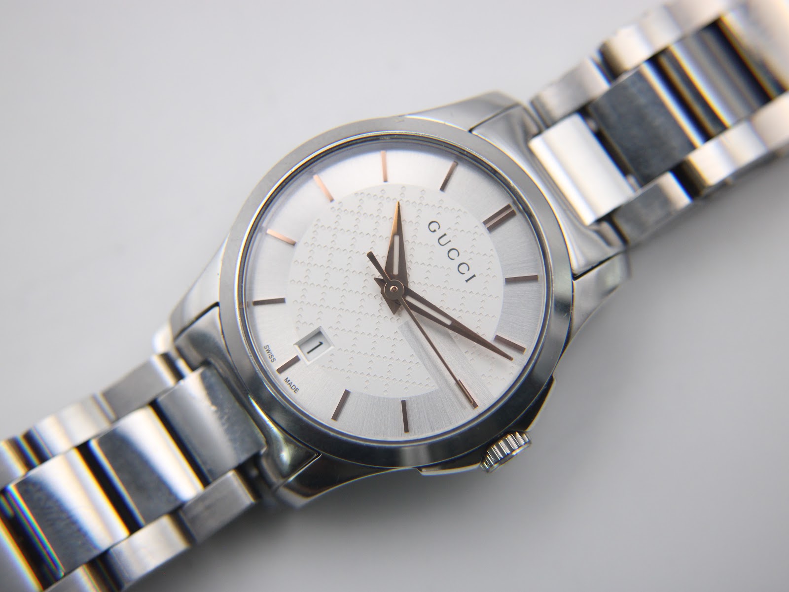 Overhead angled close-up of the Gucci 126.5 watch dial and bracelet, showing the textured centre and date window.
