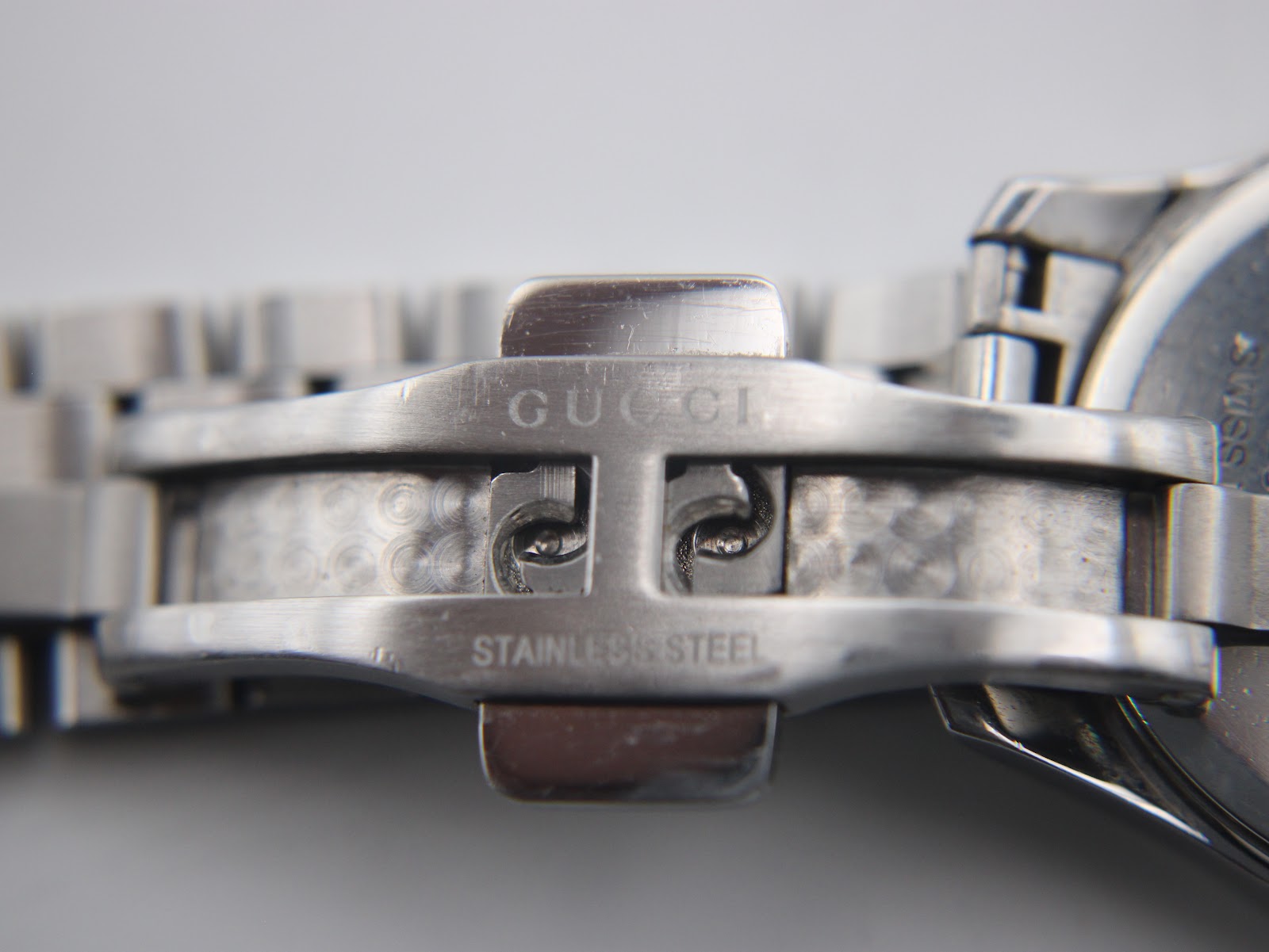 Close-up of the interior of the stainless steel folding clasp, engraved with 'GUCCI' and 'STAINLESS STEEL'.
