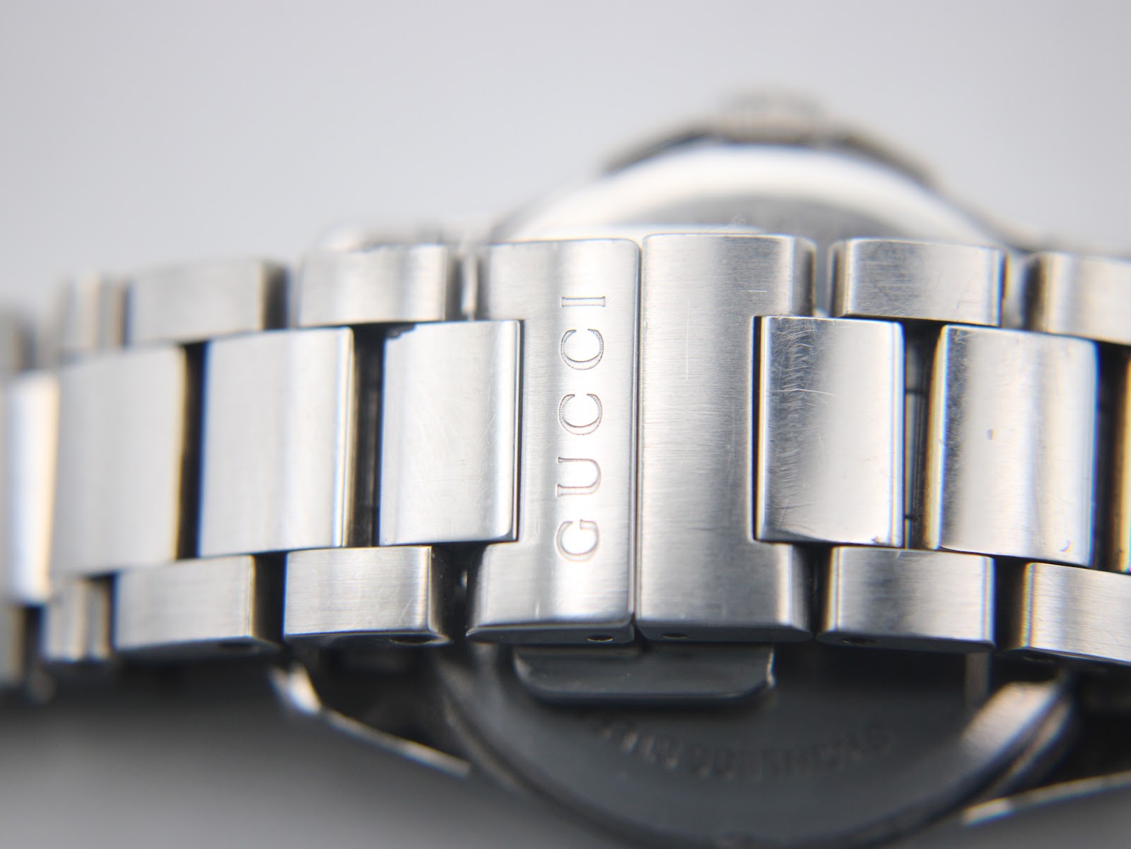 Close-up of the exterior of the stainless steel bracelet clasp, showing the 'GUCCI' engraving on one of the links.
