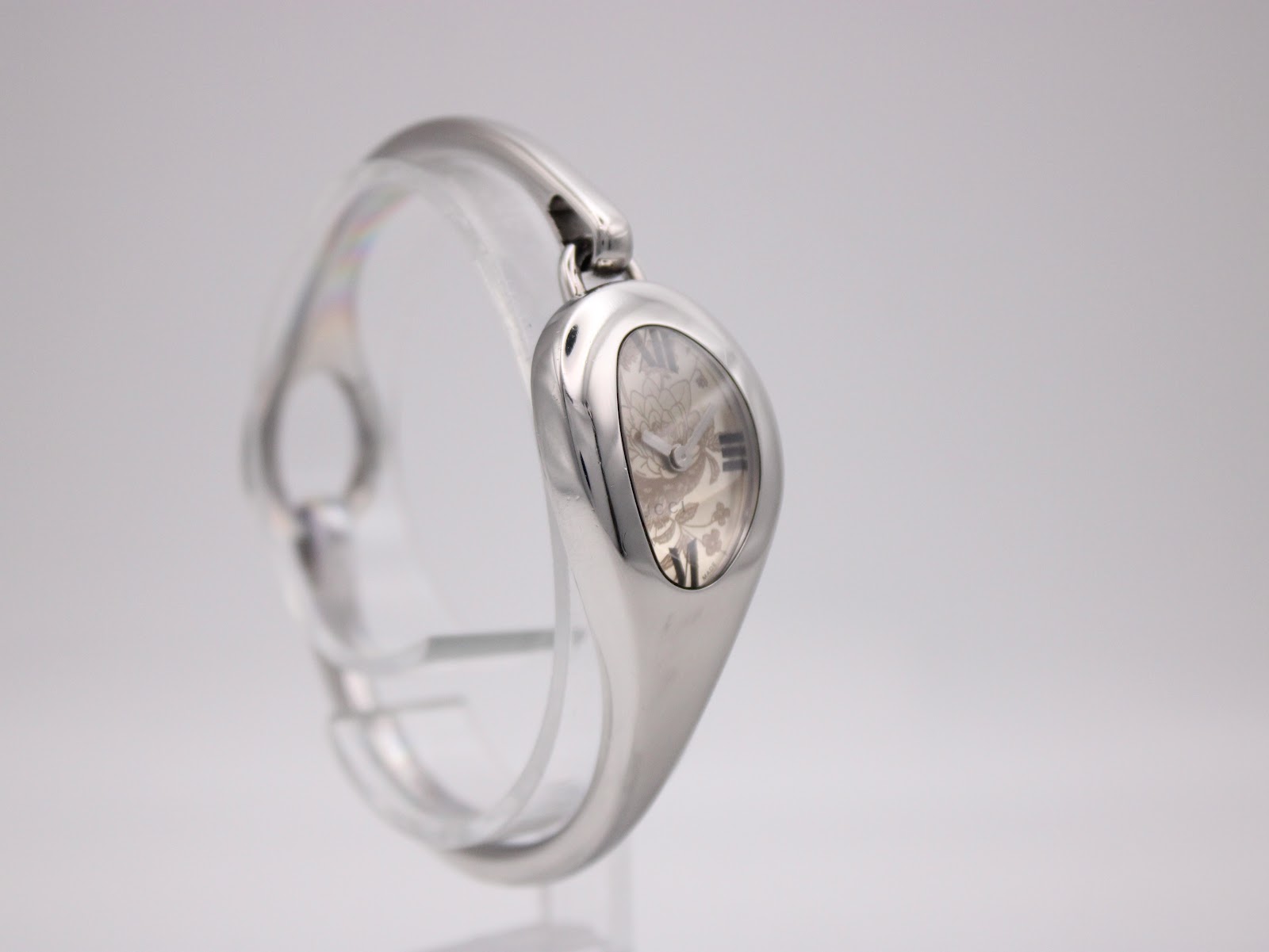 Angled side view of the Gucci 103 watch with its integrated silver bracelet, showcasing the oval shape.