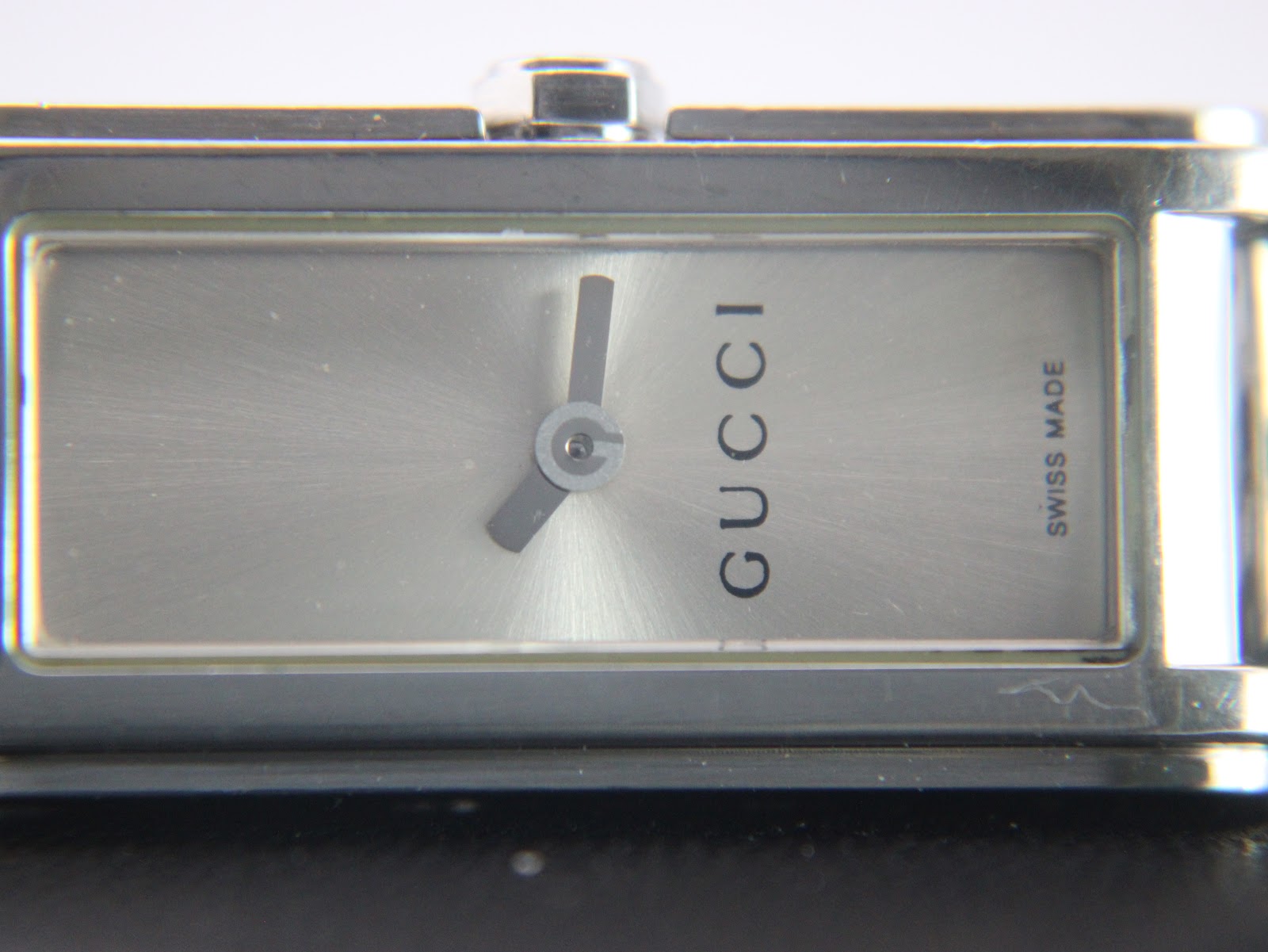 Extreme close-up of the watch dial, detailing the minimalist hands and textured silver face.