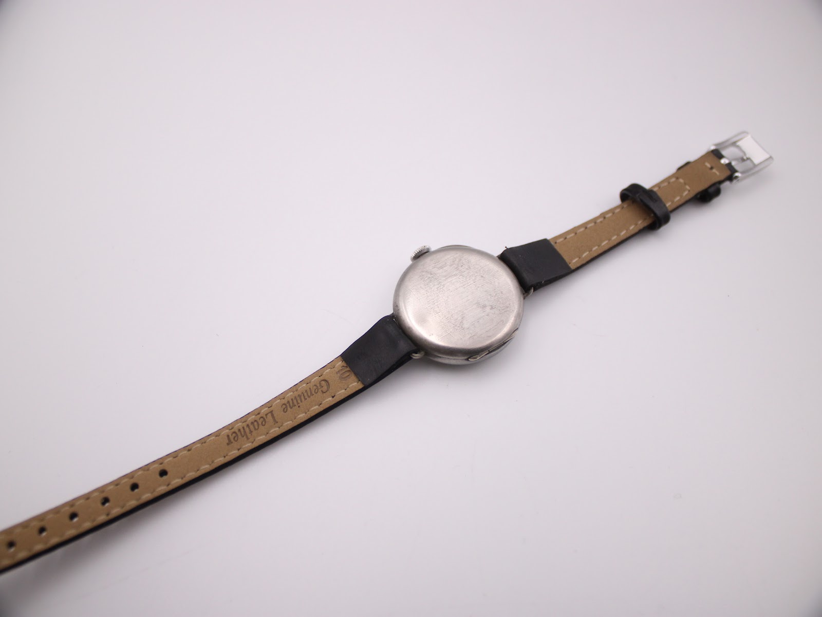 Rear view of the Longines watch on a flat surface, displaying the plain case back and the 'Genuine Leather' marking on the strap interior.