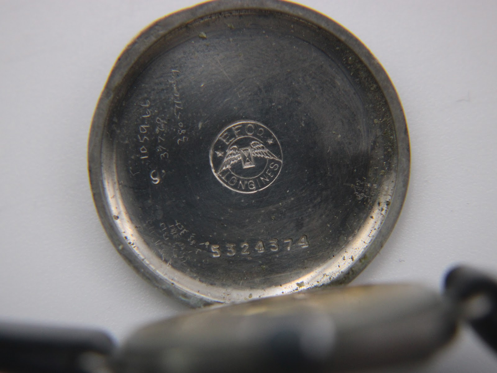 Detailed view of the inside of the case back, showing the Longines winged hourglass logo, serial number 5324374, and internal markings.