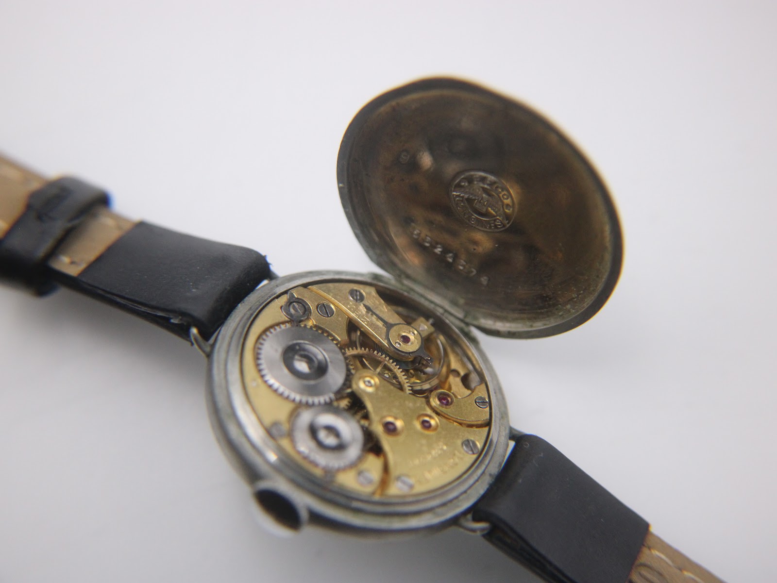 Oblique view of the Longines watch with its movement cover open, showing the intricate golden gears and balance wheel.