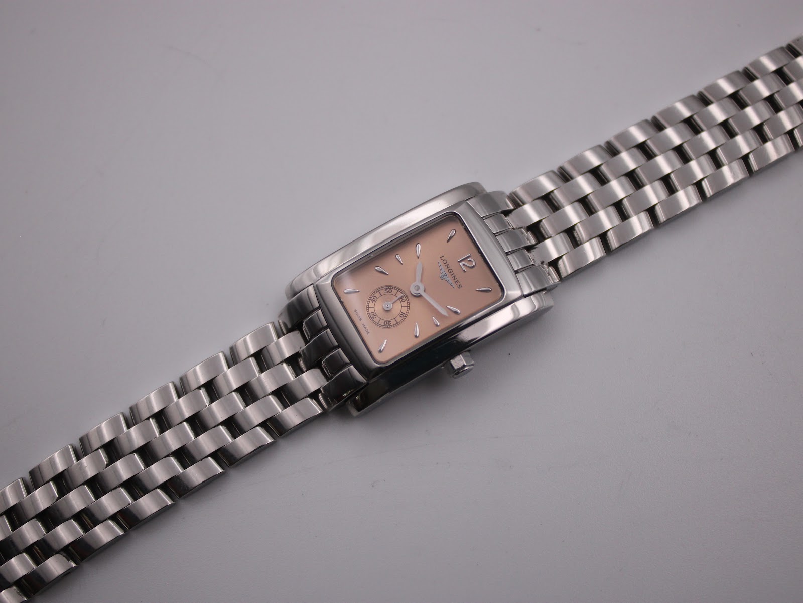 Overhead angled view of the Longines 7751 watch, focusing on the entire length of the stainless steel bracelet and dial.