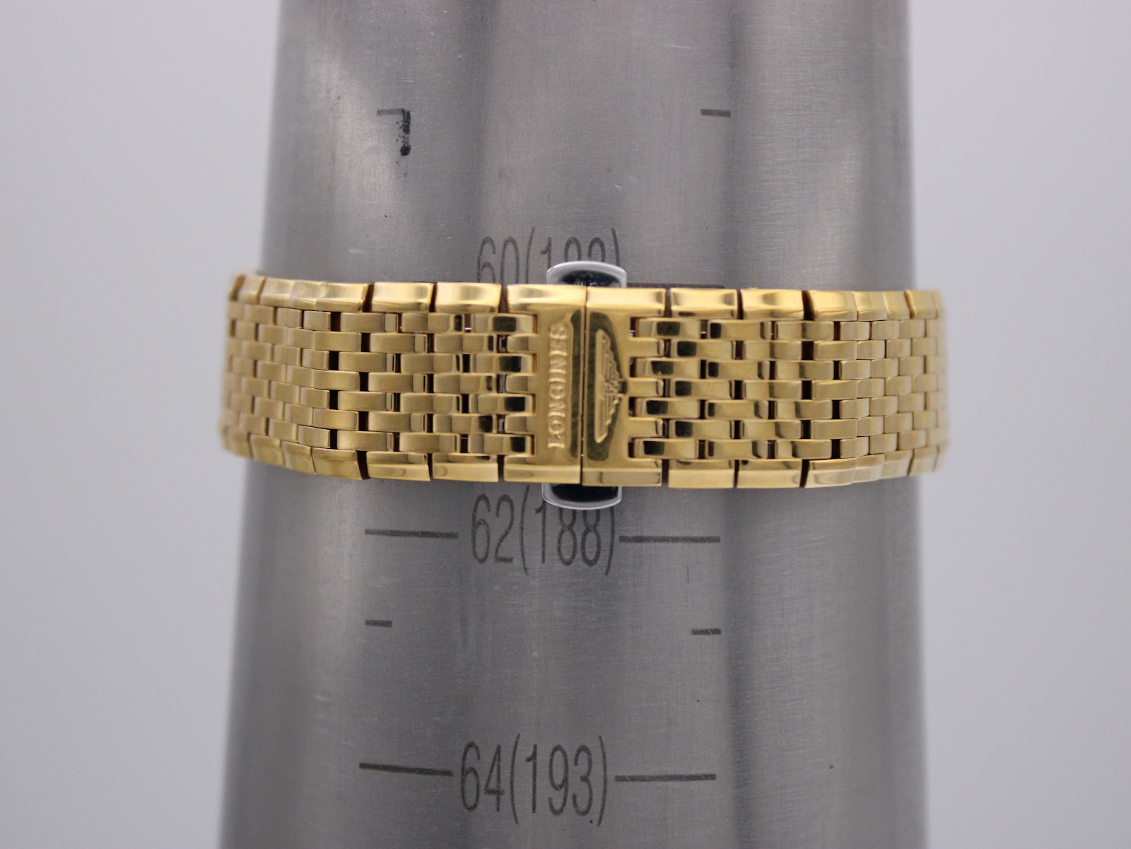 The gold multi-link bracelet on a wrist sizing gauge, showing a measurement of 62 (188) mm.