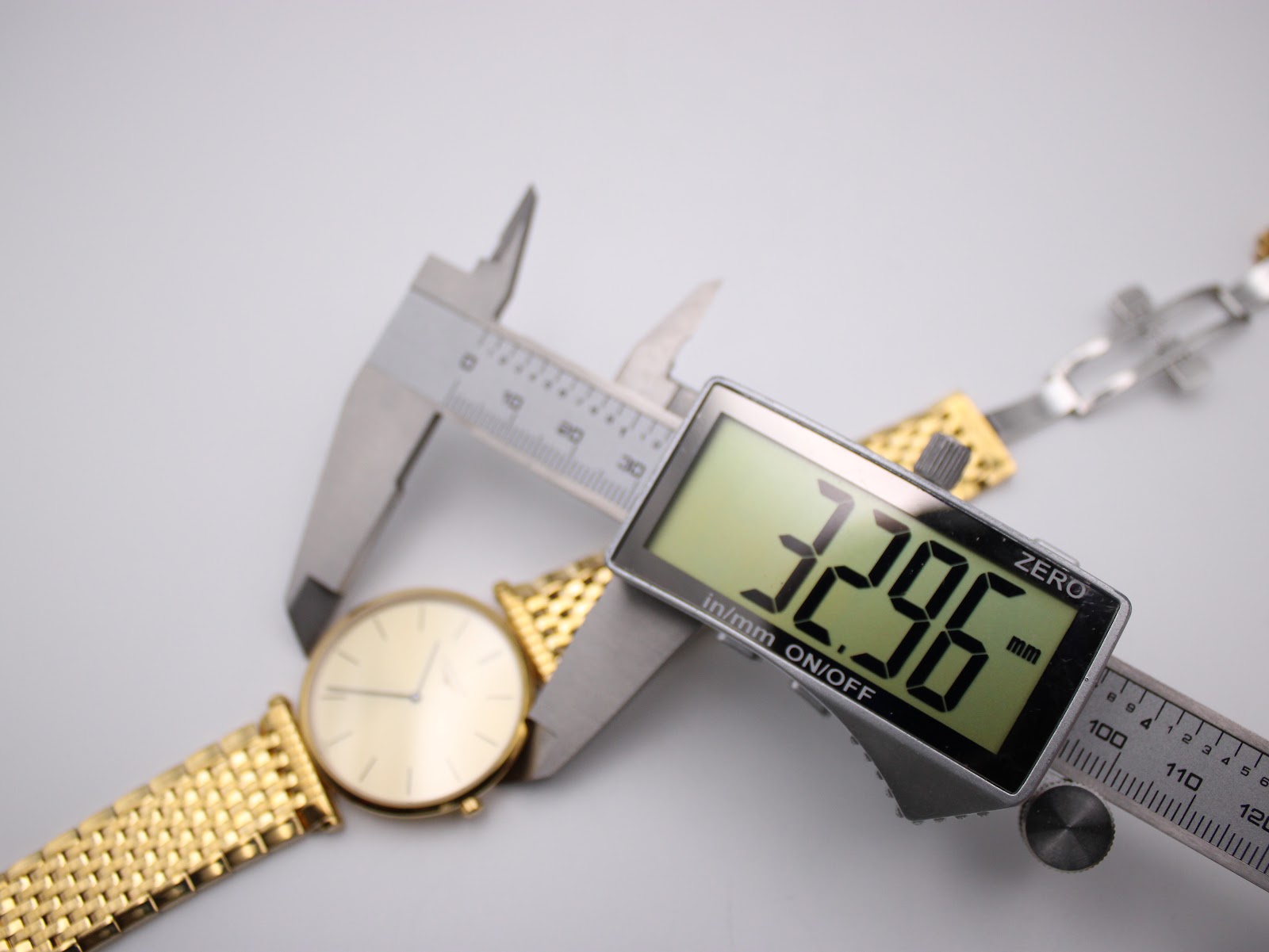 Digital caliper measuring the case diameter of the Longines watch, displaying 32.96mm.