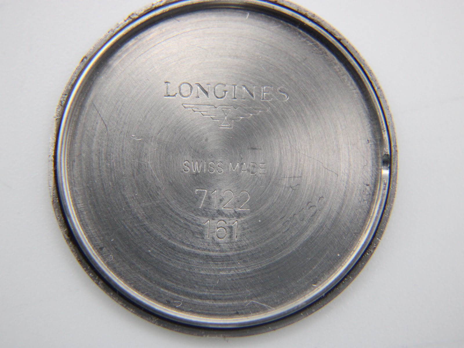 Close-up of the inside of the stainless steel case back, showing the Longines logo, "Swiss Made", and model number 7122.