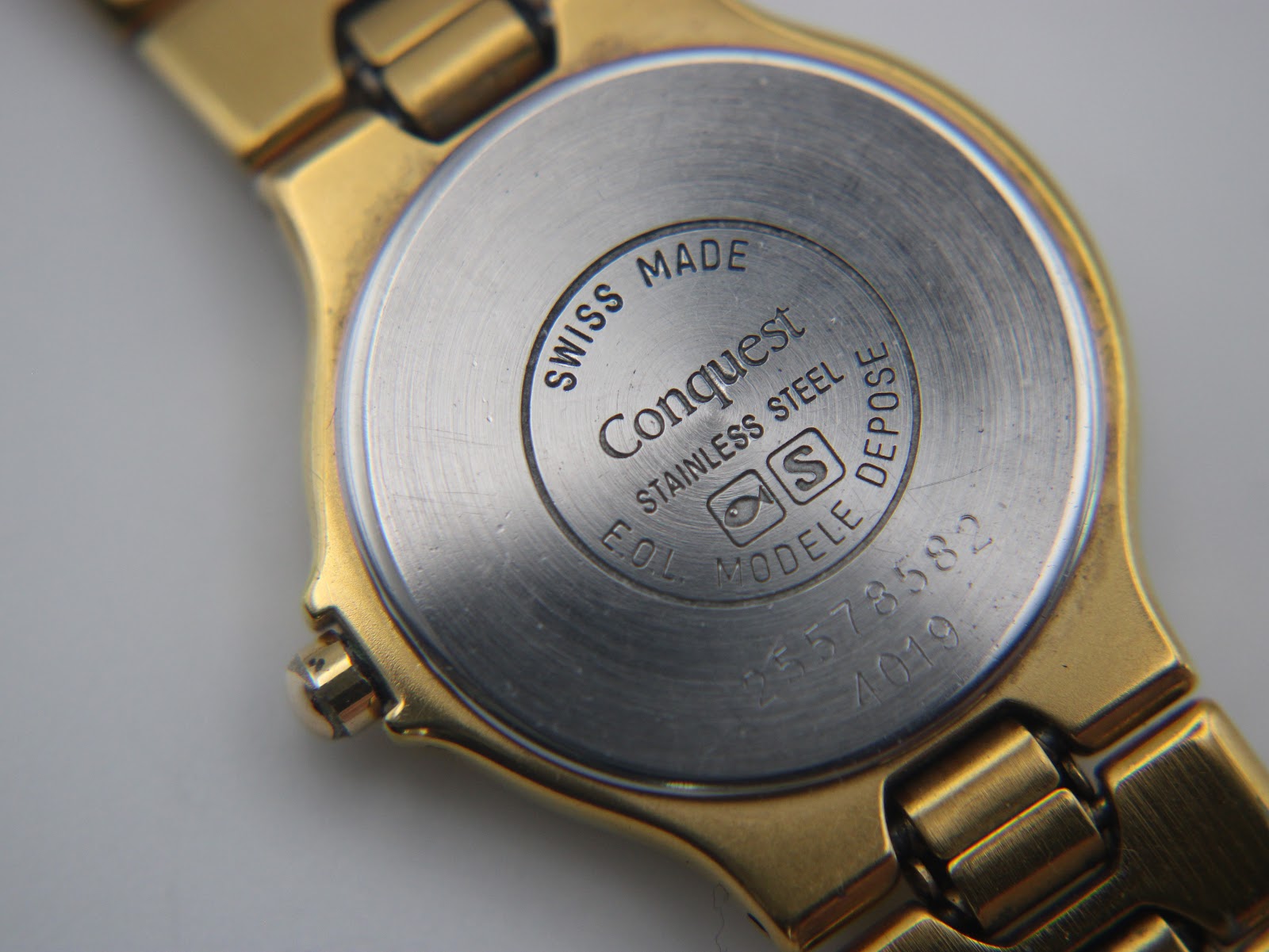 Close-up of the stainless steel case back with "Swiss Made", "Conquest", serial number 25573582, and "Stainless Steel".