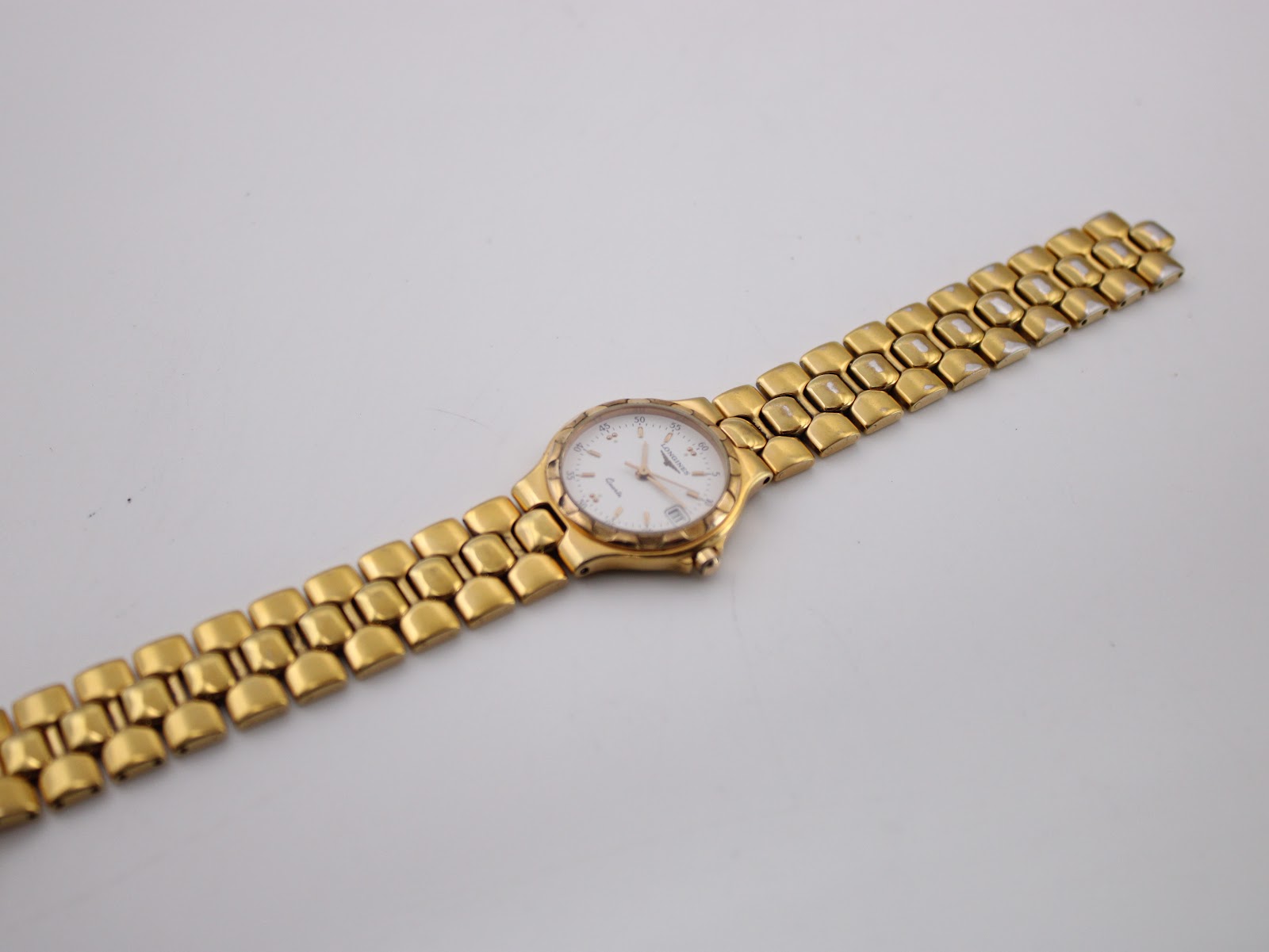 Full length top view of the Longines Conquest watch and gold-tone bracelet on a white background.