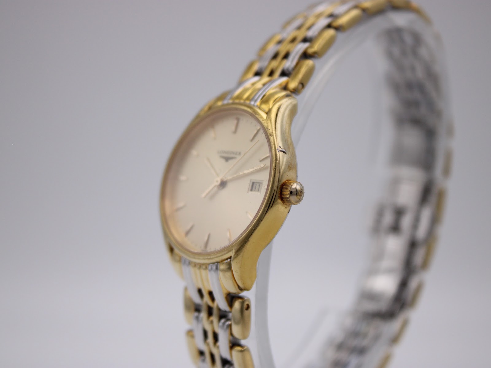 Angled side view of the Longines Lyre watch showing the gold-tone case, crown, and a small mark on the side.