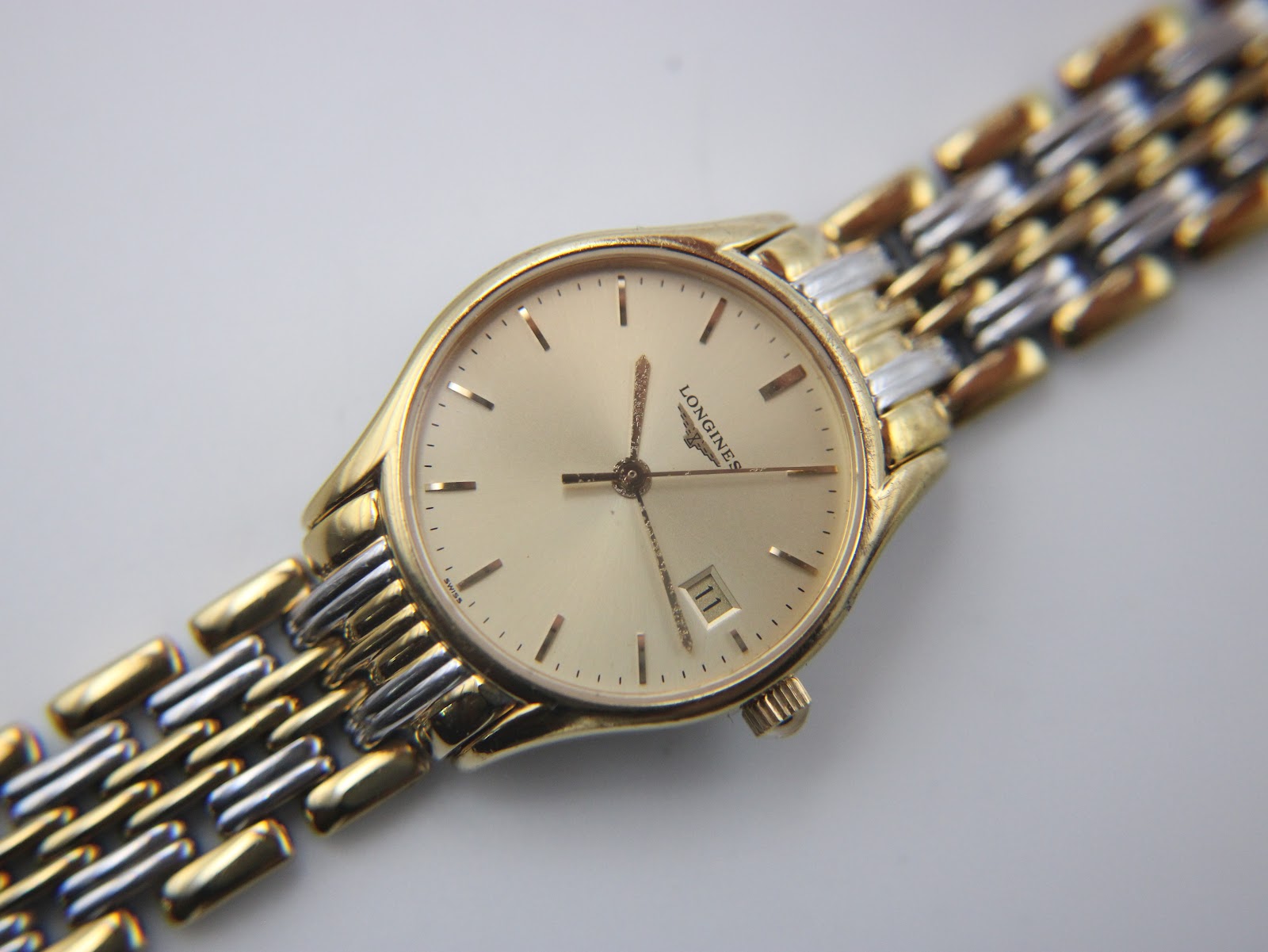 Overhead angled view of the Longines Lyre watch with its champagne dial and the full two-tone bracelet laid out.