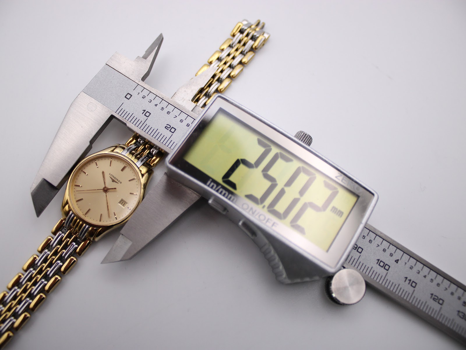 Digital caliper measuring the Longines Lyre watch case, displaying an exact diameter of 25.02mm.