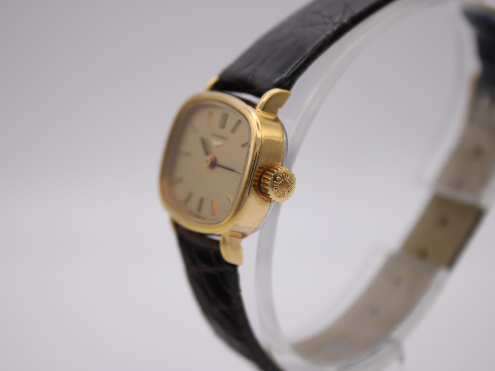 Side view of the Longines watch showing the gold cushion case and signed crown.