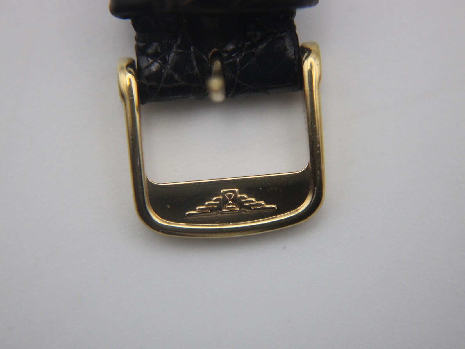 Close-up of the gold tone buckle, featuring the Longines winged hourglass logo.