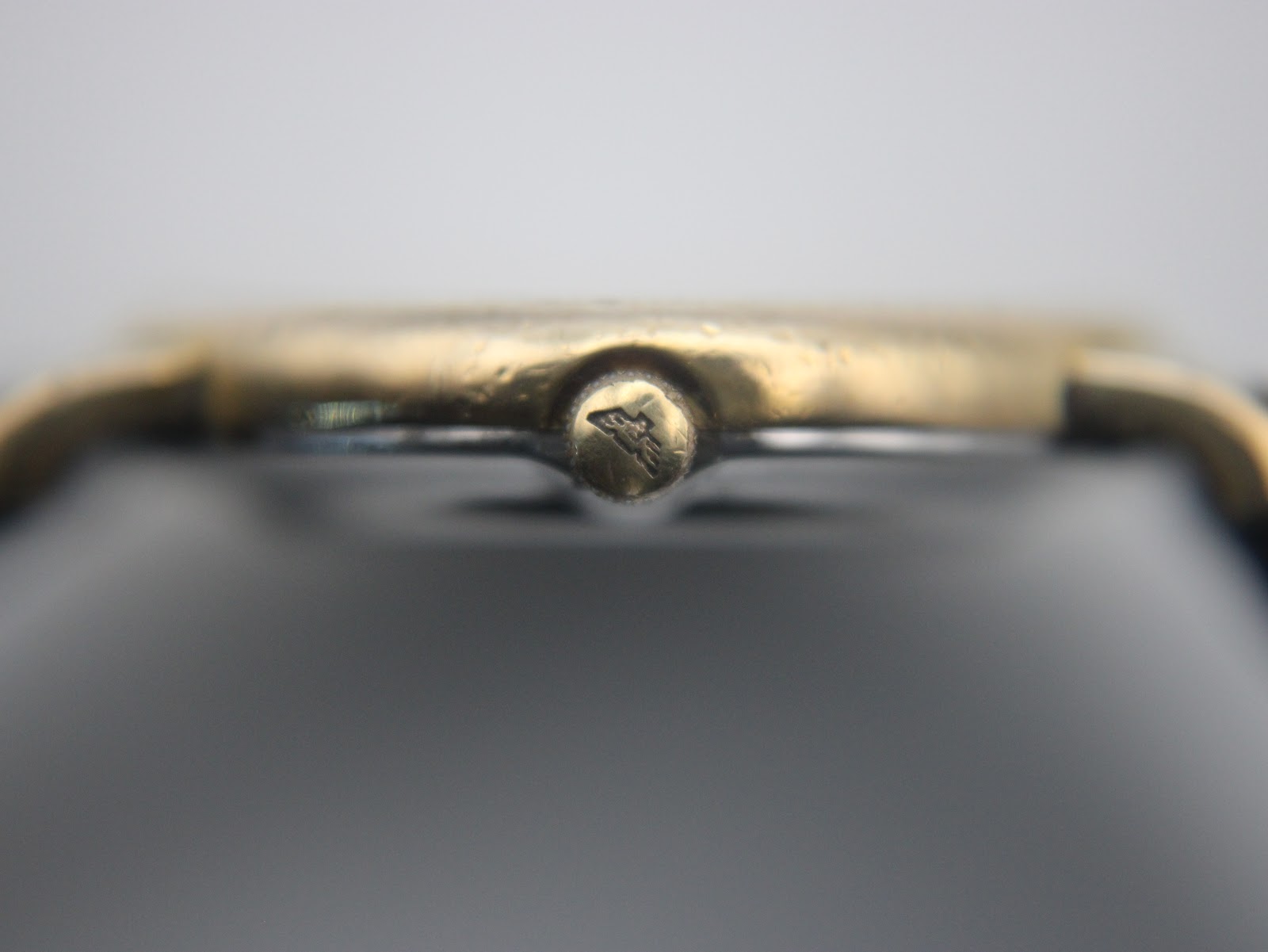 Macro shot of the watch crown, clearly showing the embossed Longines winged hourglass logo.