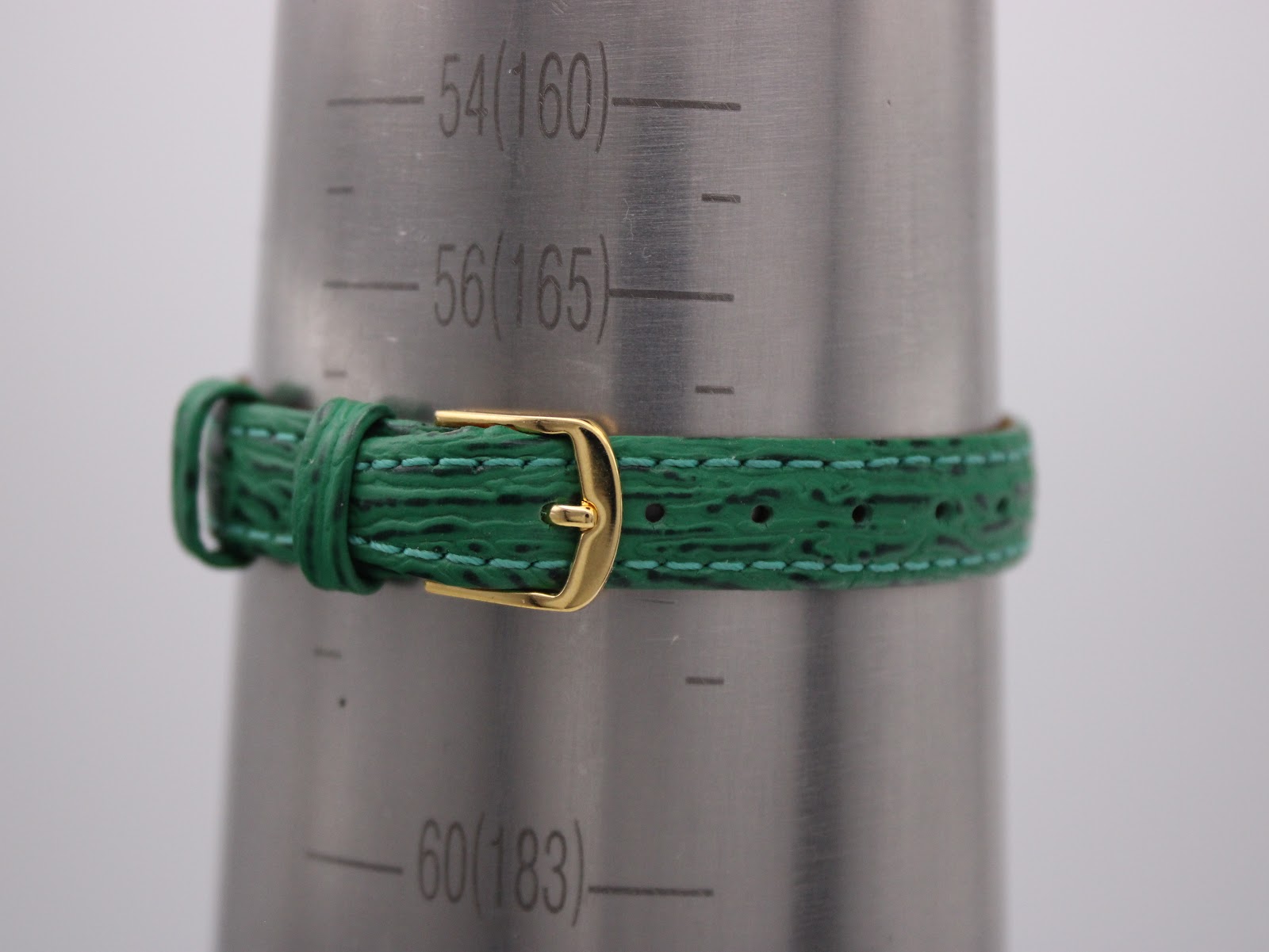 Close-up of the green leather strap fastened on a wrist sizing gauge, showing it fits a wrist of approximately 16.5cm.