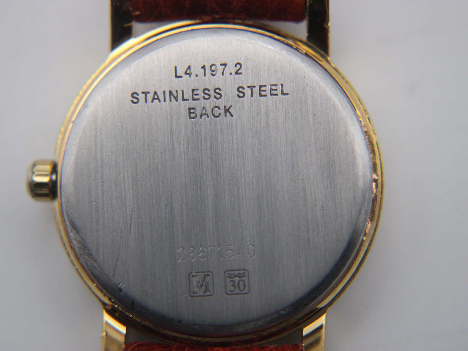 Close-up of the watch case back, engraved with model L4.197.2, 'STAINLESS STEEL BACK', serial 28871540, and water resistance marking '30'.