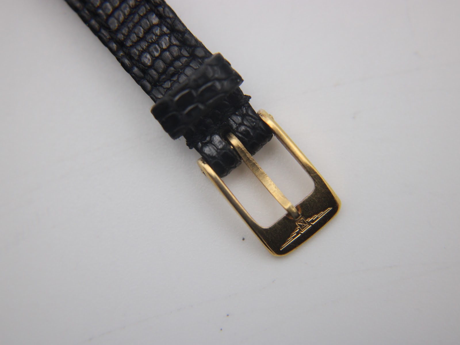 Close-up of the gold-tone pin buckle with the engraved Longines winged hourglass logo.