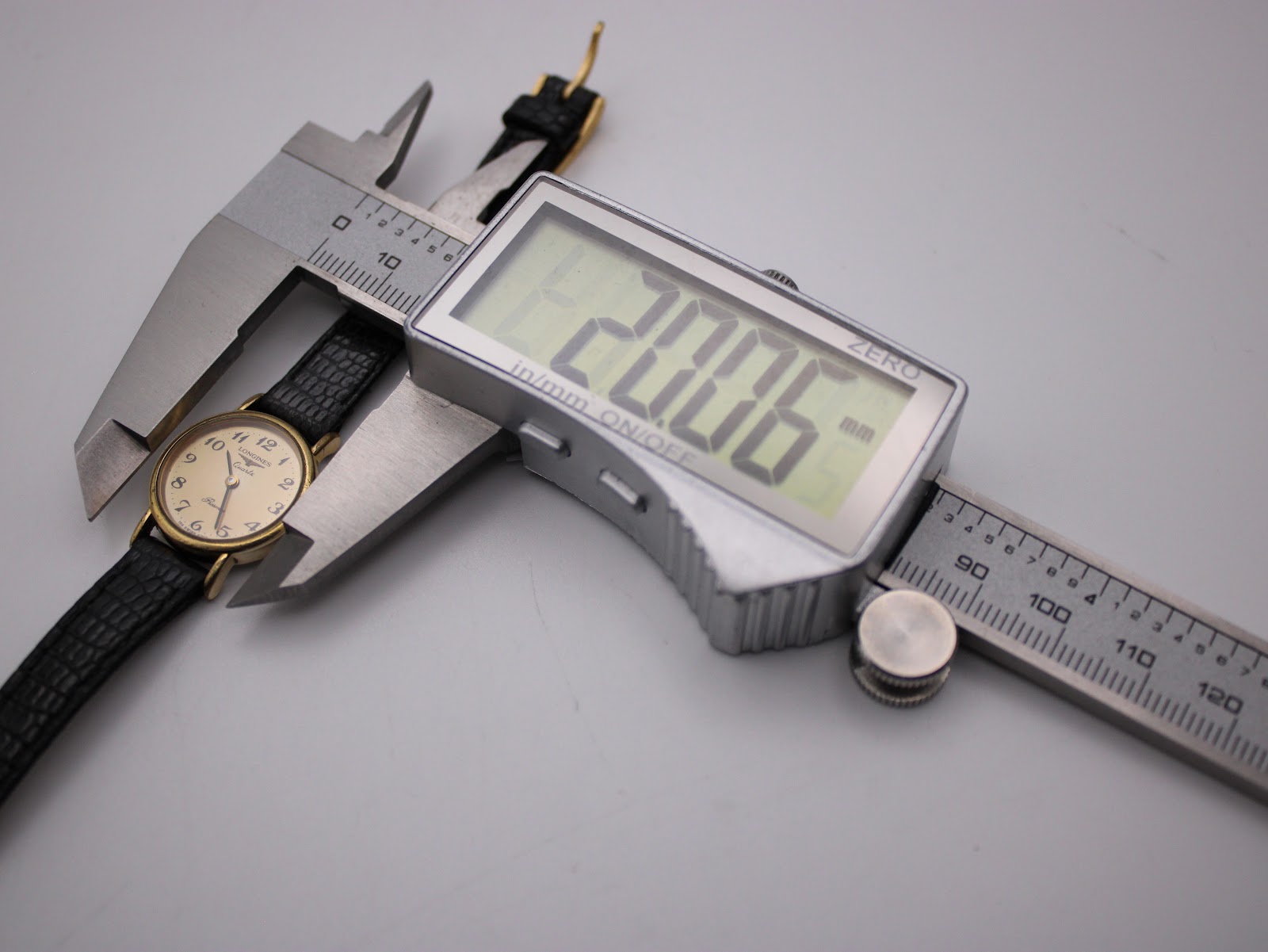 Digital caliper measuring the watch case, displaying a precise diameter of 20.06mm.