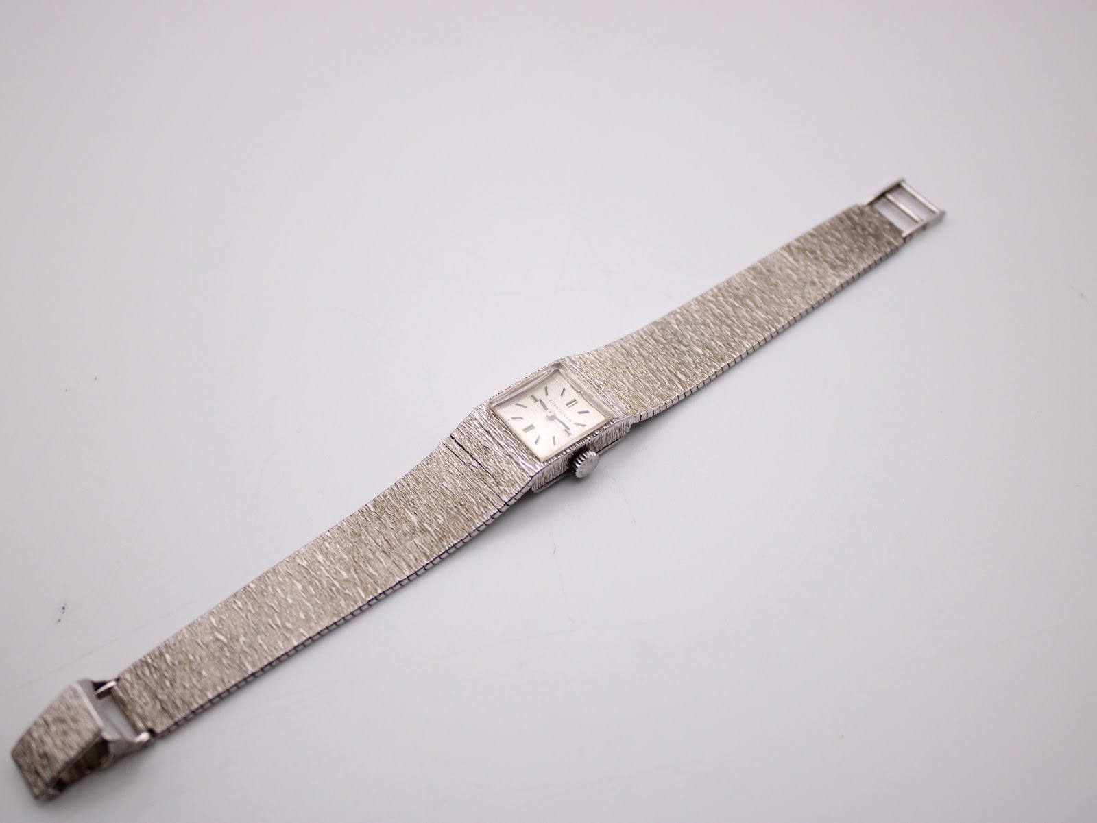 Top-down view of the full Longines watch with its textured sterling silver integrated bracelet laid flat.