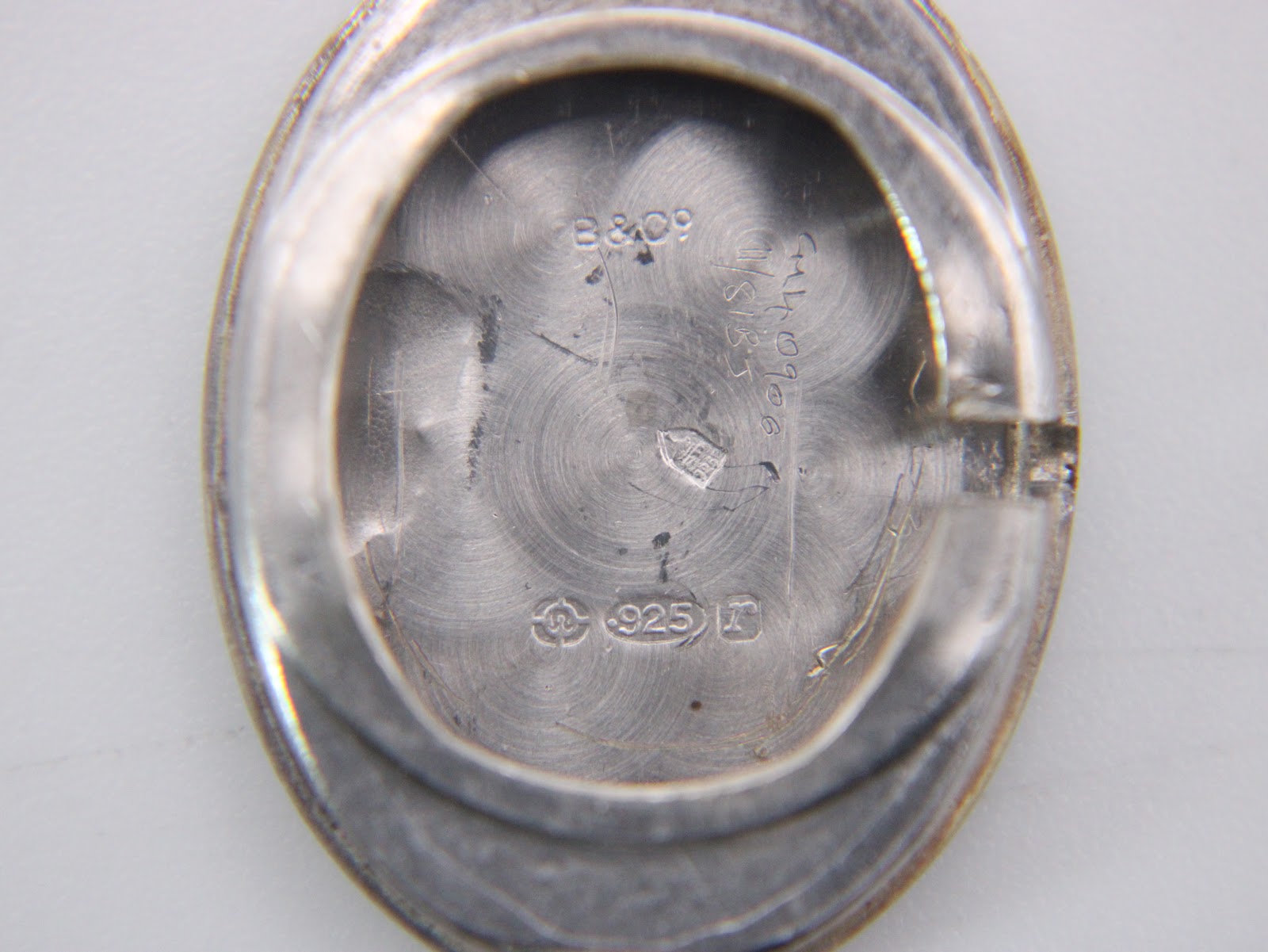 Inside view of the silver case back, showing a '925' sterling silver hallmark, 'B & Q9', and a distinct jeweller's symbol.
