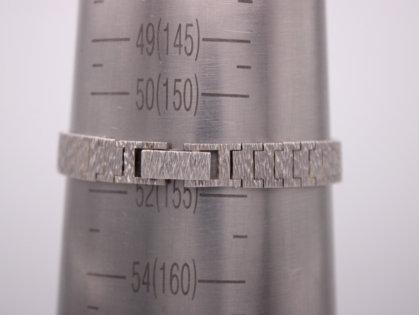 Wrist sizing gauge showing the custom-made silver bracelet measuring approximately 155mm or 15.5cm in circumference.