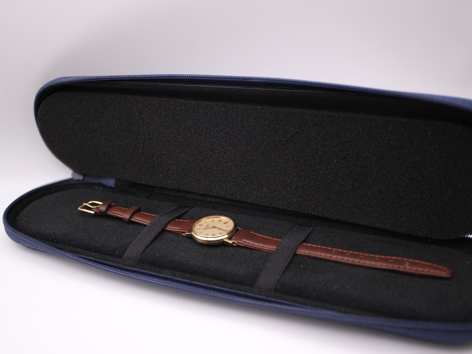 The Longines watch nestled inside its open blue original Longines travel case, showing the soft interior.