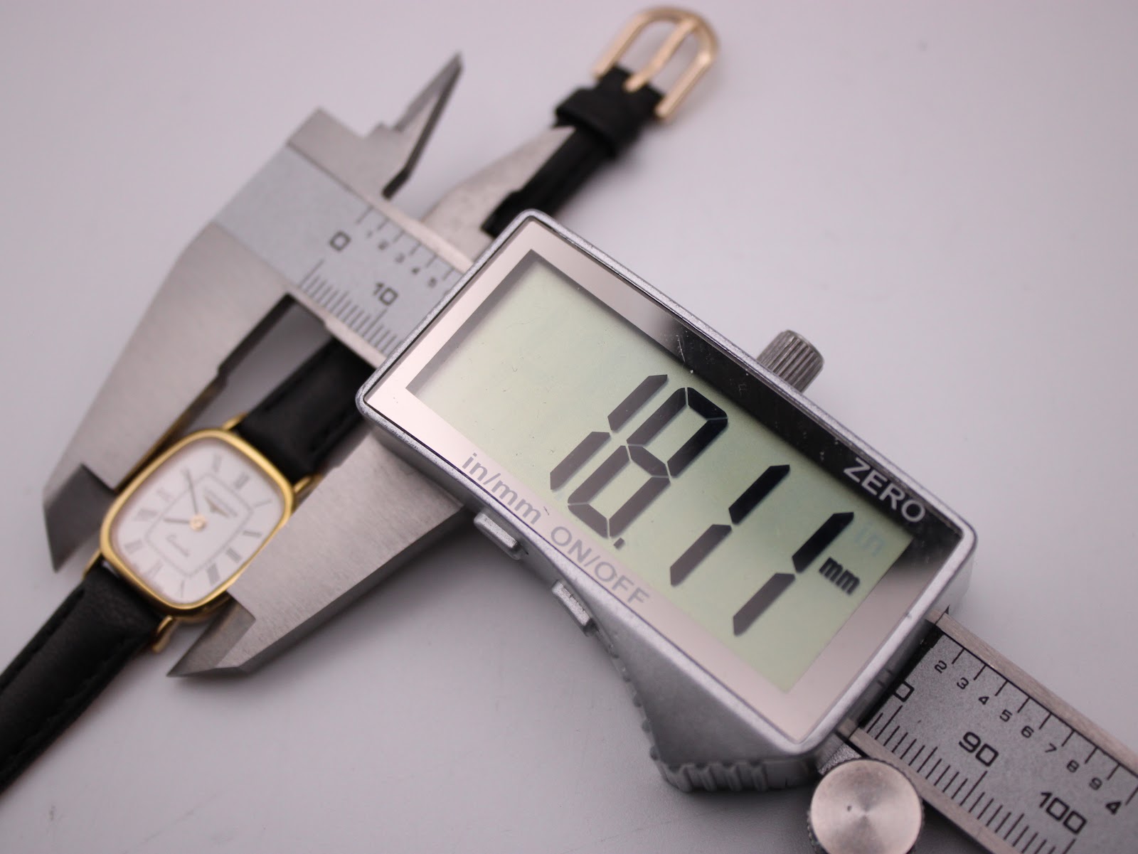 Digital caliper measuring the case diameter of the Longines watch, displaying 18.11mm.